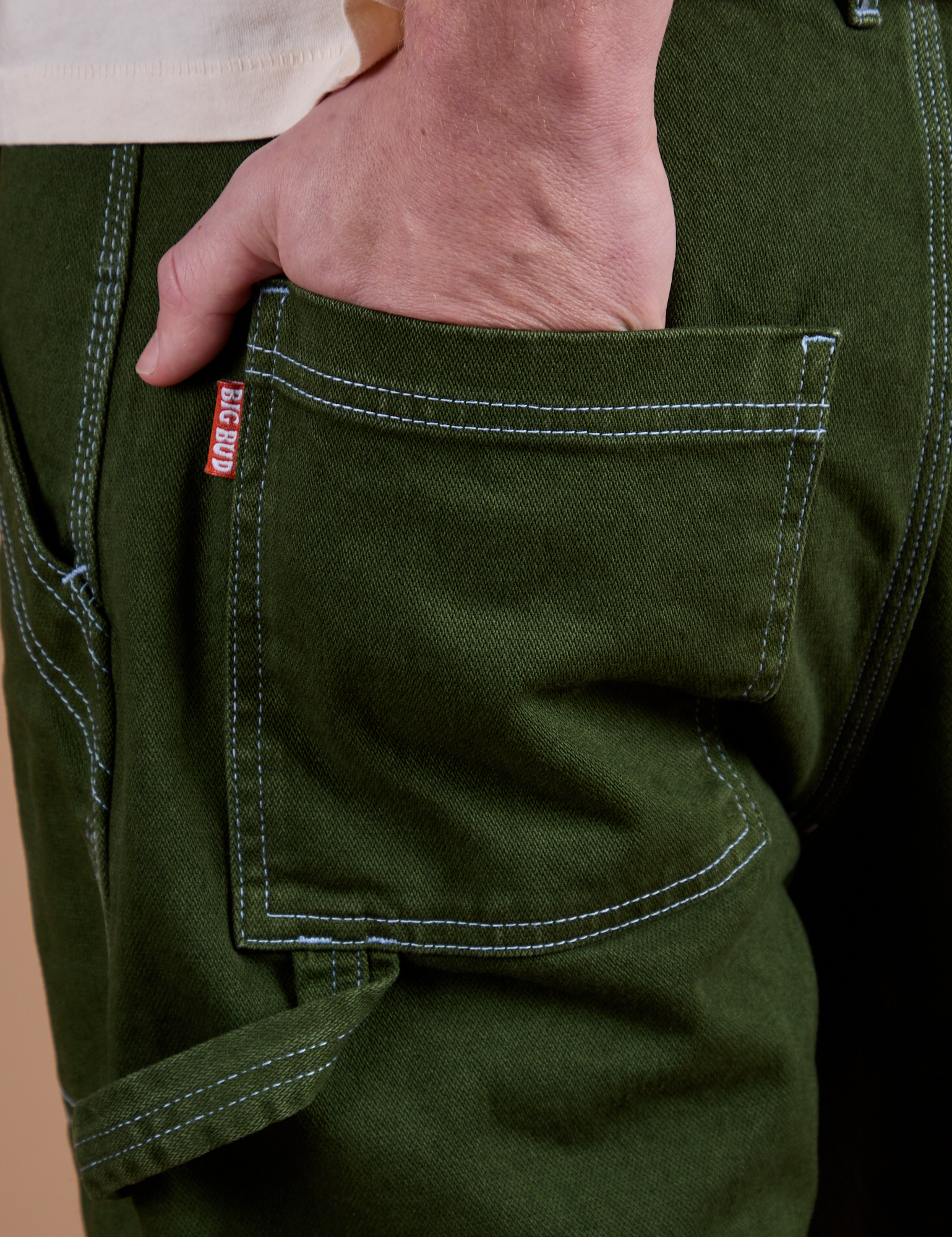 Close up of Quinn's hand in the back pocket of Carpenter Jeans in Evergreen