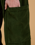 Close up of Alex's hand in the pant leg side pocket of Corduroy Drop Pocket Cargo Pants in Evergreen