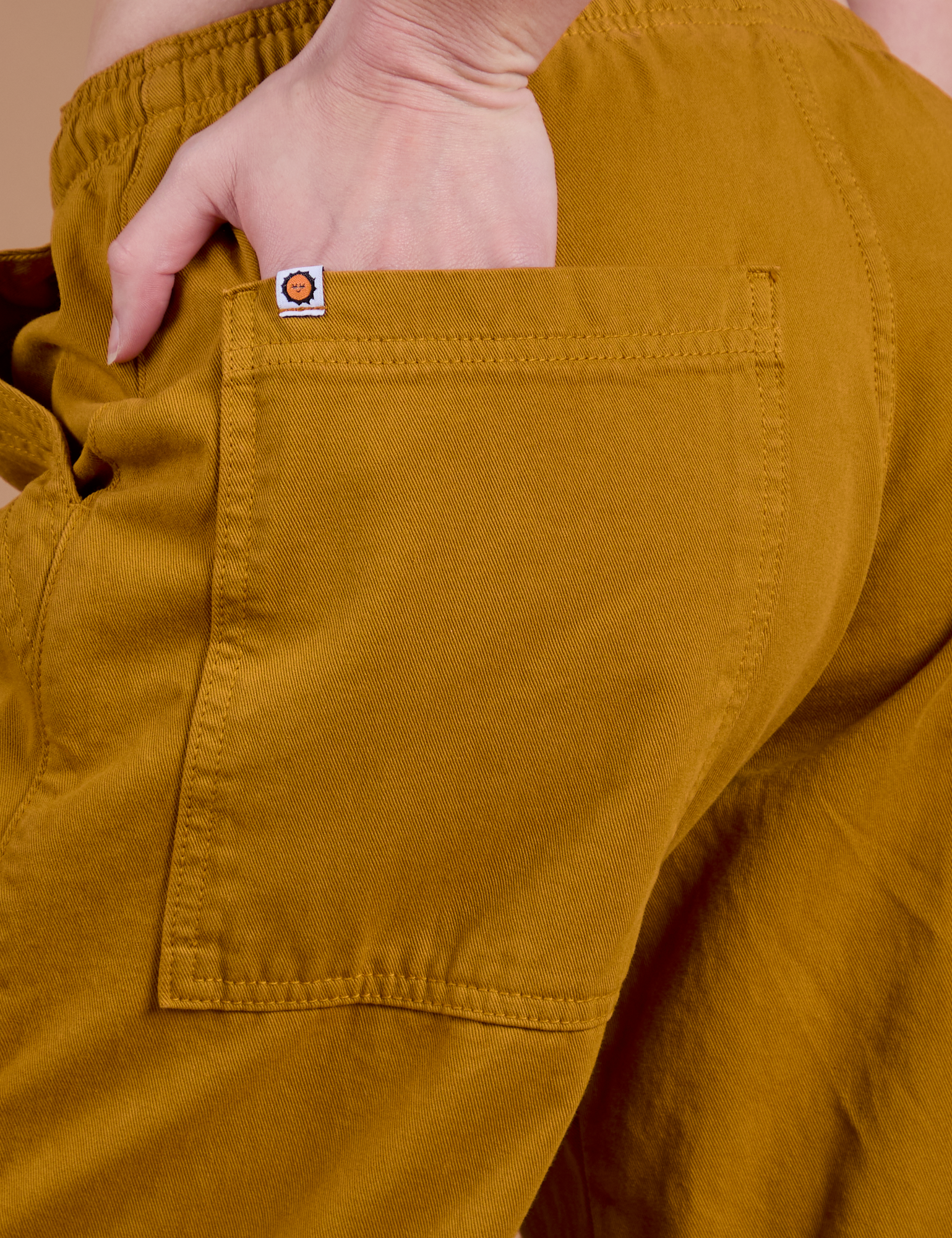 Close up of Alex's hand in the back pocket of Drop Pocket Cargo Pants in Spicy Mustard 