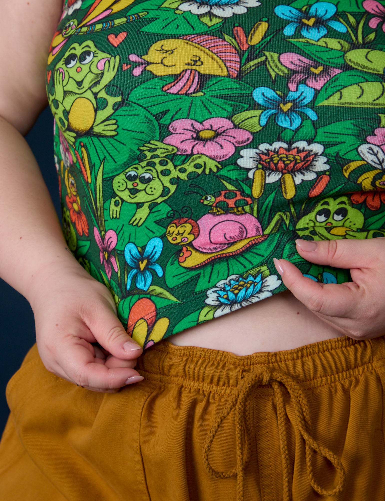 Close up of Ashley holding the hem of Pond Party Racerback Tank