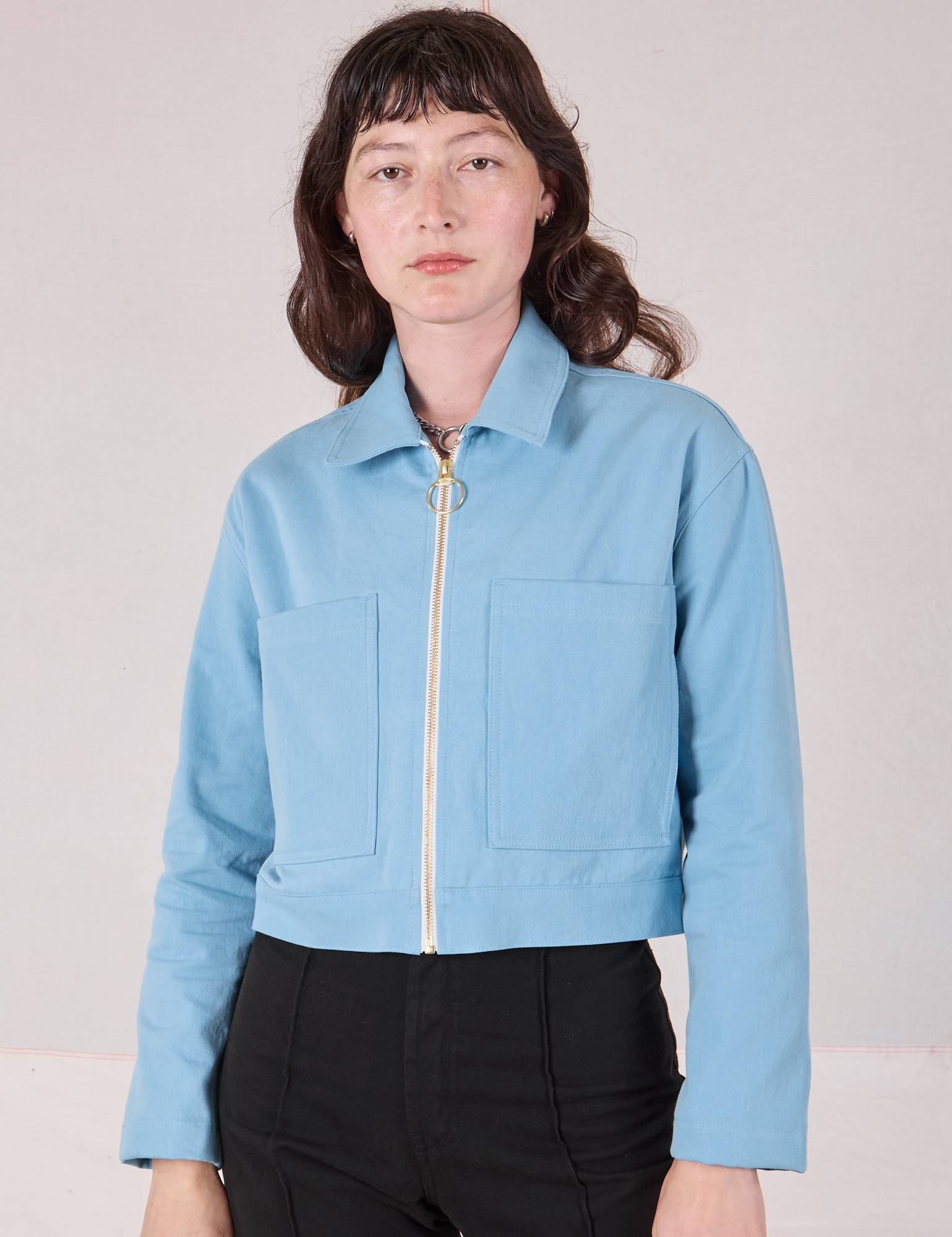 Alex is wearing a zipped up Mechanic Jacket in Baby Blue