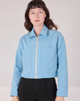 Alex is wearing a zipped up Mechanic Jacket in Baby Blue