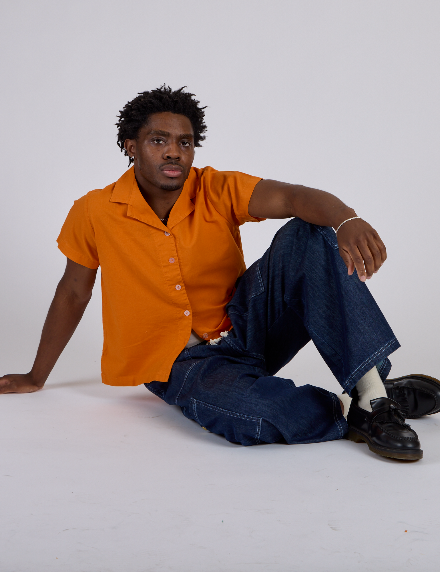 Isaac is wearing Pantry Button-Up in Creamsicle Orange and dark wash Denim Drop Pocket Pants