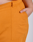 Close up of Juliet's hand in the front pocket of  Work Pants in Creamsicle Orange