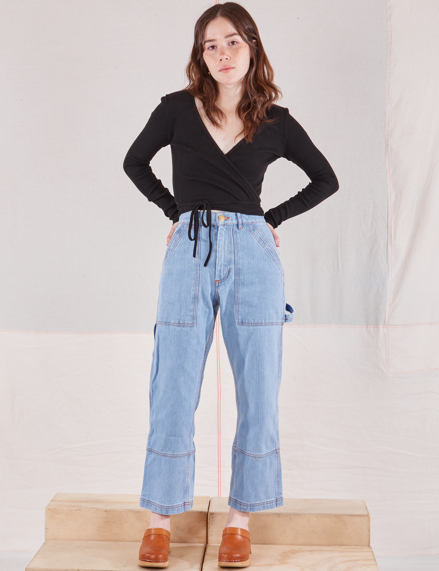 Hana is wearing Wrap Top in Basic Black and light wash Carpenter Jeans