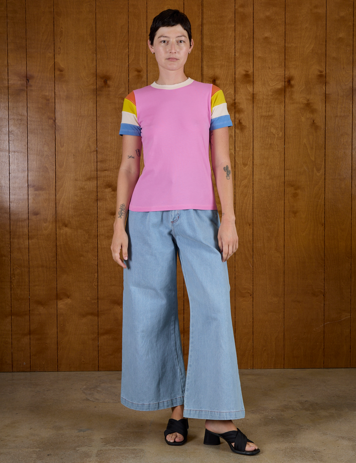 Alex is 5'8" and wearing P Calypso Tee in Bubblegum Multi paired with light wash wide leg denim trousers