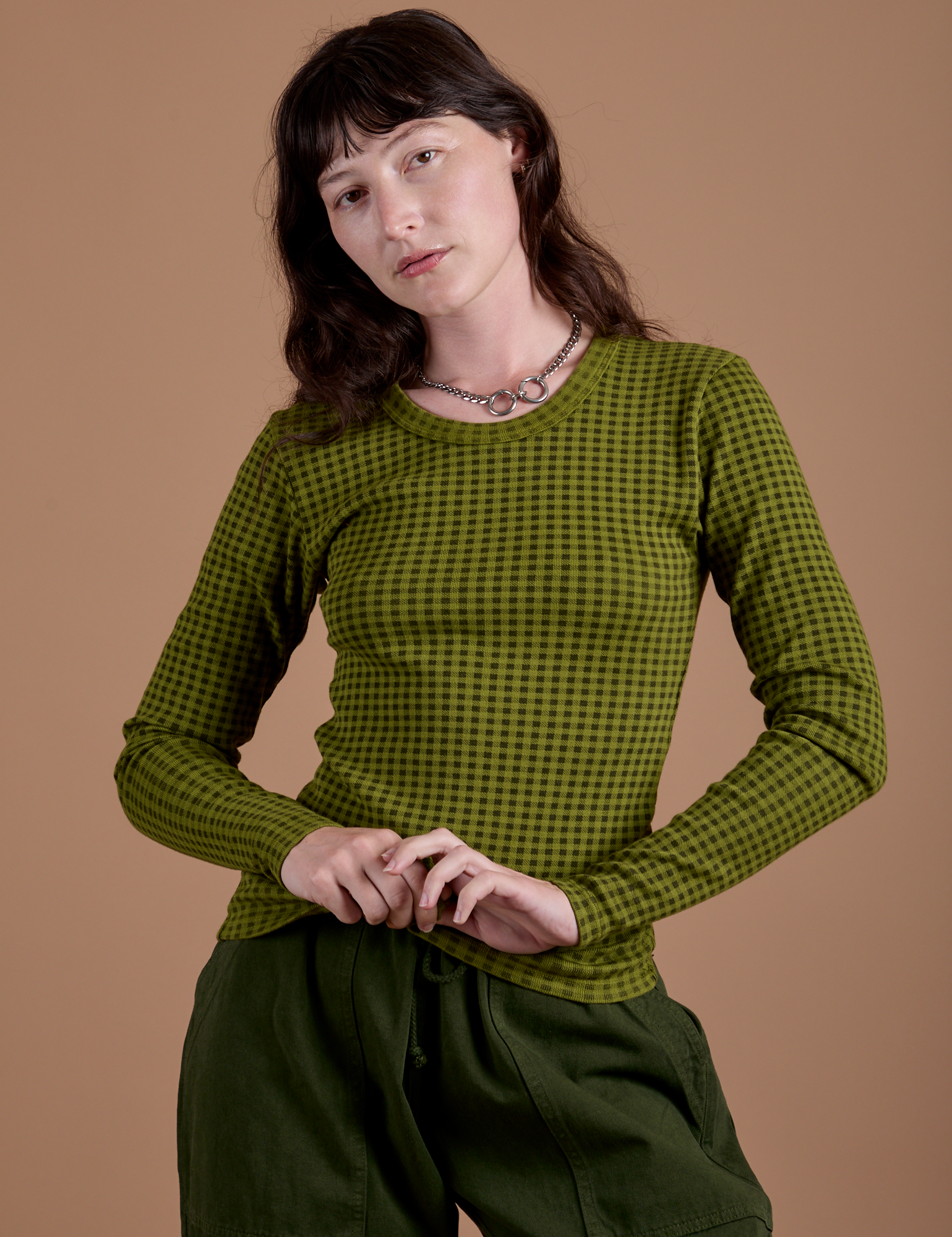 Alex is 5’8” and wearing XP Gingham Long Sleeve Baby Tee in Summer Olive