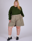 Juliet is 5’7” and wearing 2XL Pleated Trouser Shorts in Khaki Grey paired with evergreen Long Sleeve Burly Tee