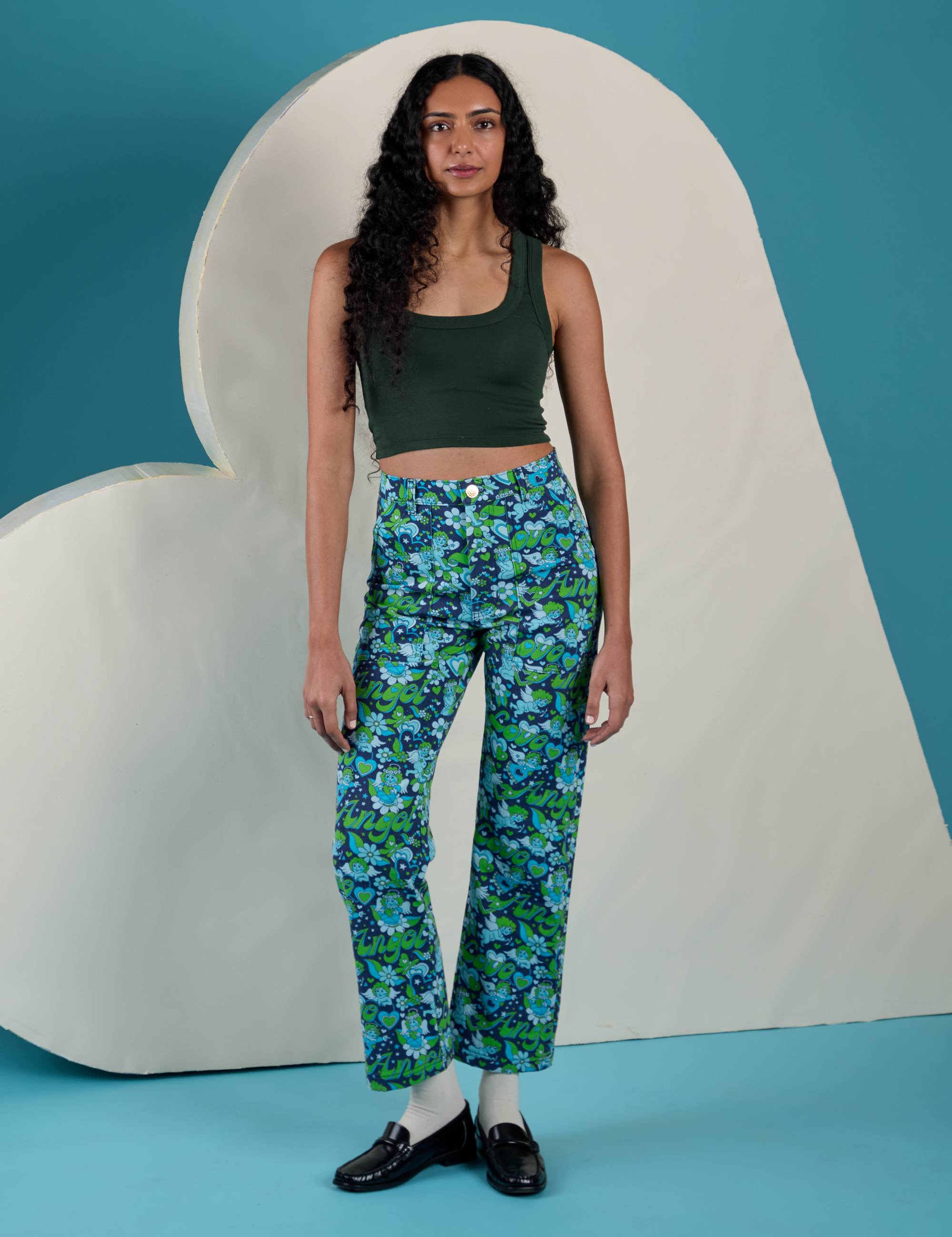 Shahana is 5’10 and wearing XS Work Pants in Angel Print paired with a swamp green Cropped Tank