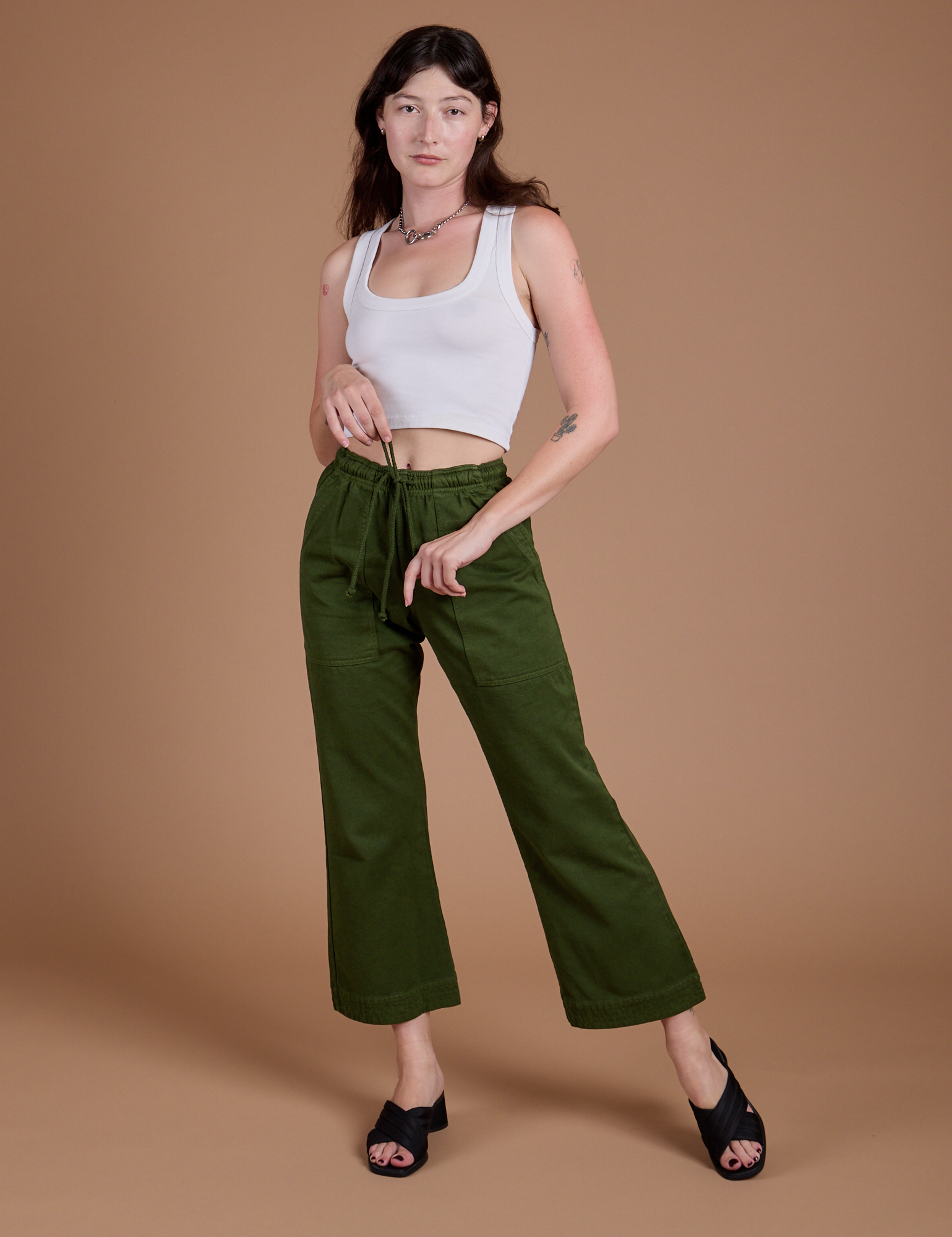 Alex is 5'8" and wearing XXS Organic Action Pants in Evergreen paired with vintage tee white Cropped Tank