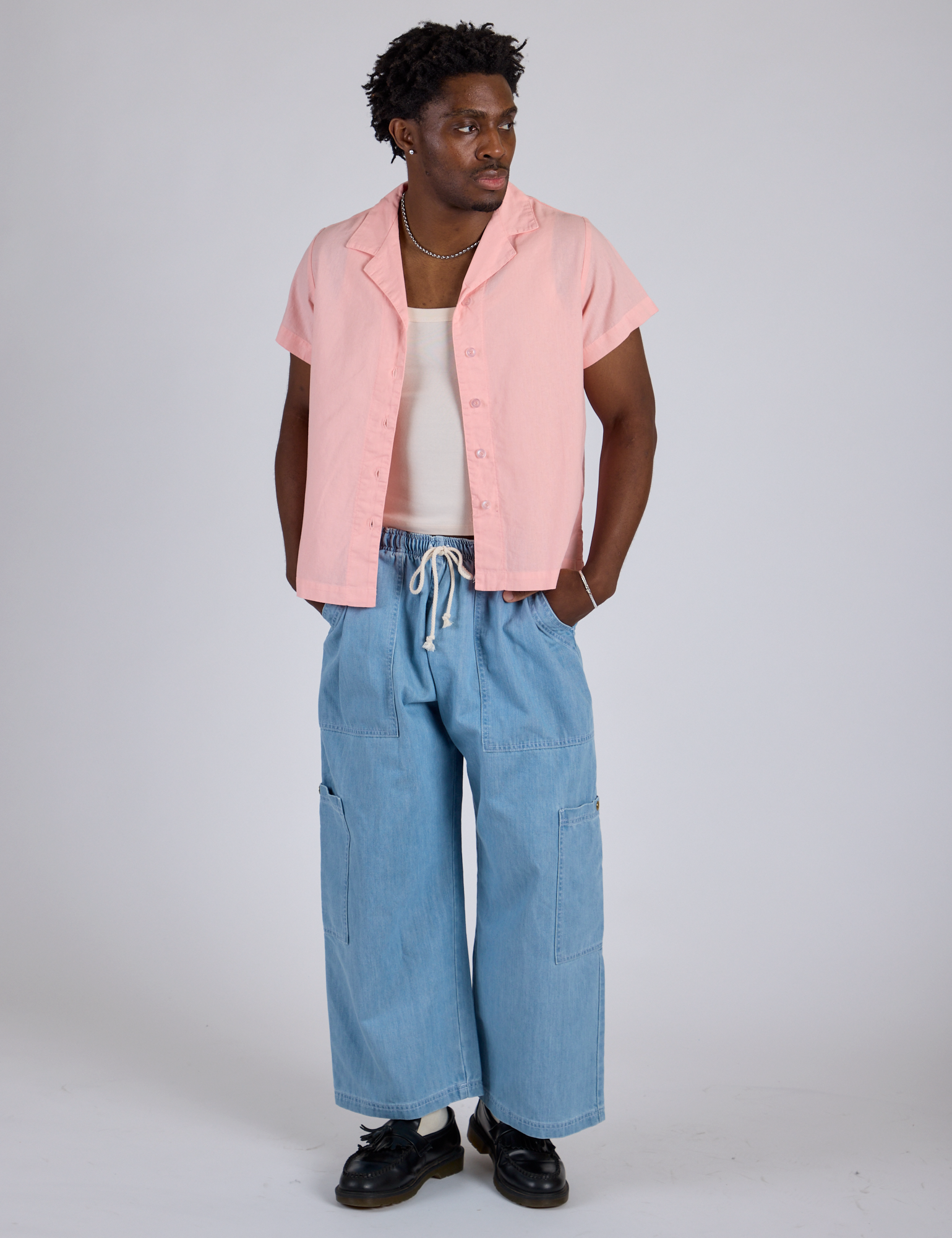 Isaac is wearing Pantry Button-Up in Baby Pink and light wash Denim Drop Pocket Pants