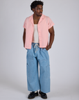 Isaac is wearing Pantry Button-Up in Baby Pink and light wash Denim Drop Pocket Pants