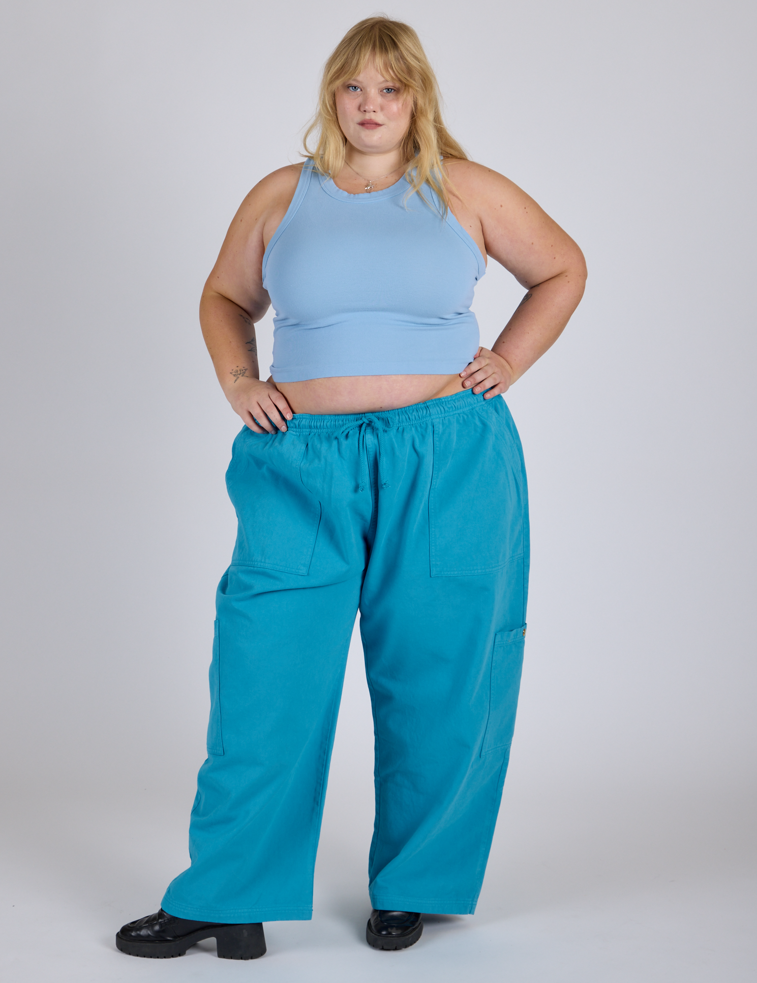 Juliet is 5’7” and wearing 2XL Drop Pocket Cargo Pants in Hawaiian Blue paired with baby blue Racerback Tank