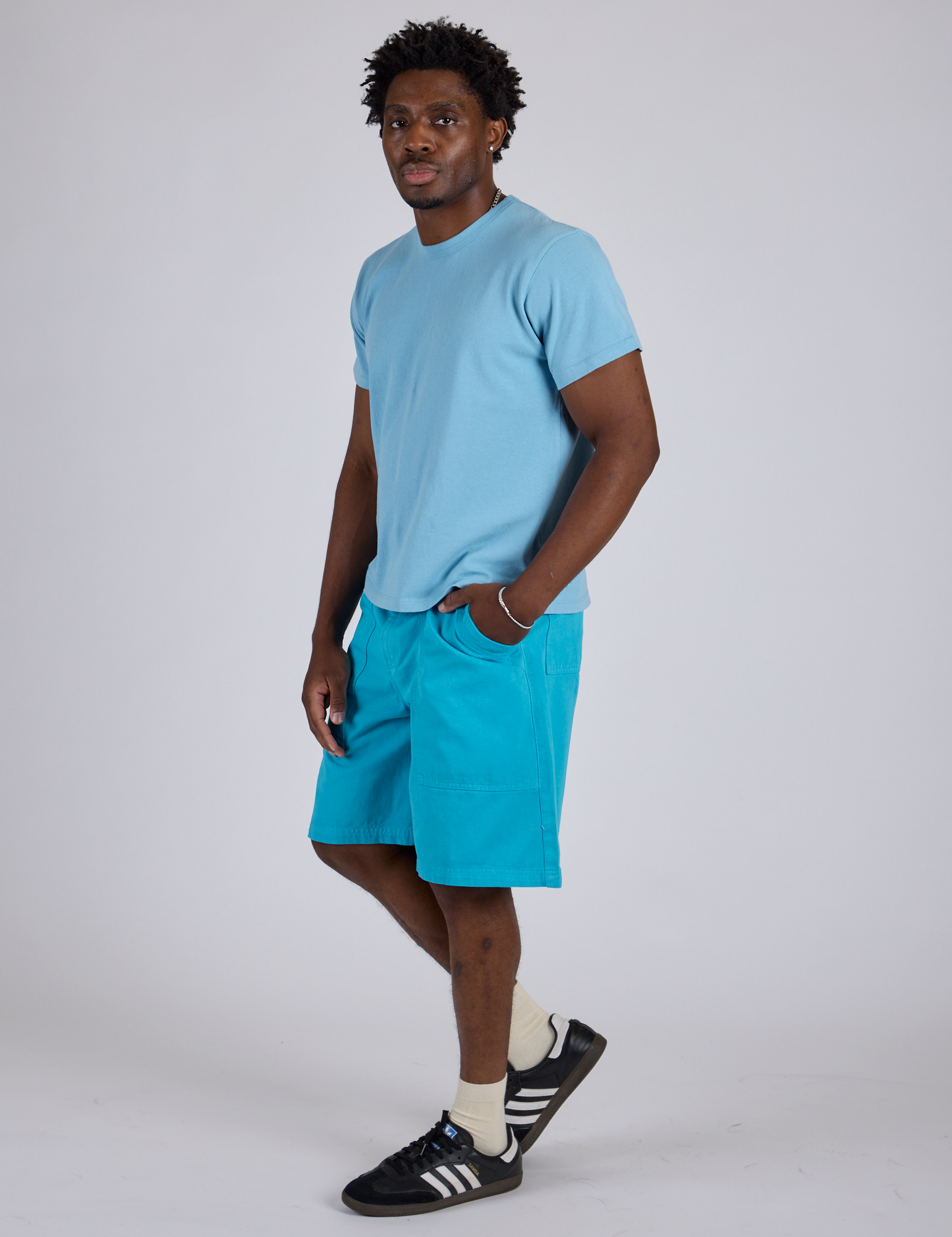 Angled front view of Longline Work Shorts in Hawaiian Blue and baby blue Organic Vintage Tee on Isaac