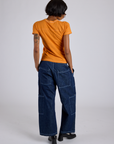 Back view of Jr. Varsity Tee in Creamsicle Orange and dark wash Denim Drop Pocket Cargo pants on Kira