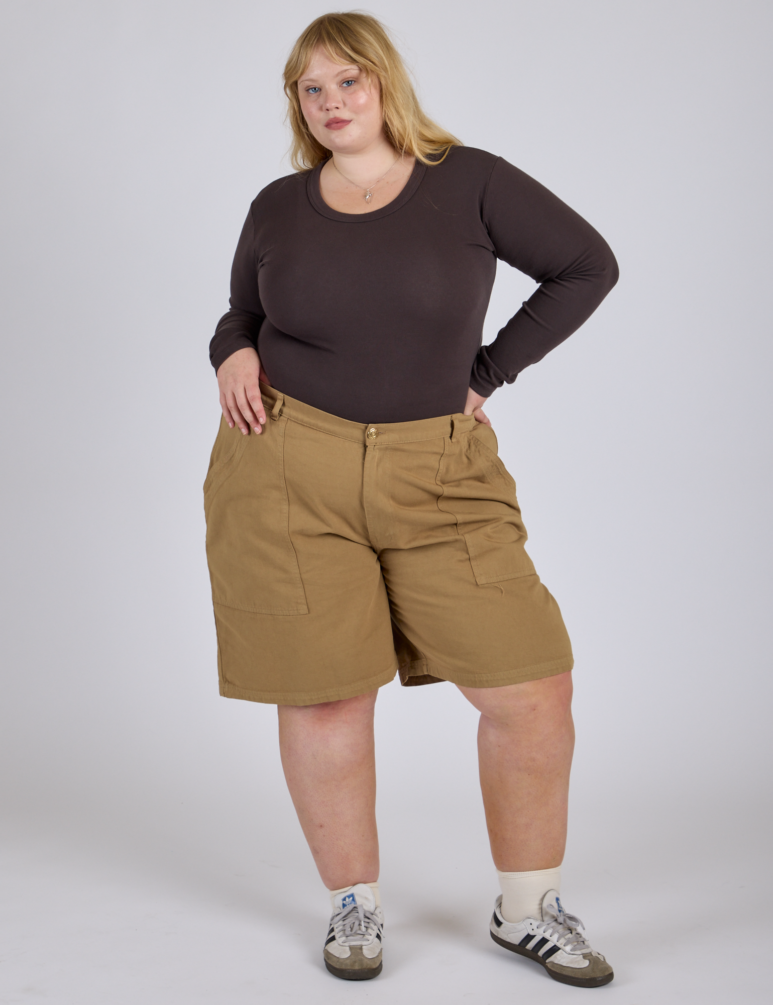 Juliet is 5’7” and wearing 2XL Longline Work Shorts in Desert Brown paired with espresso brown Long Sleeve Baby Tee