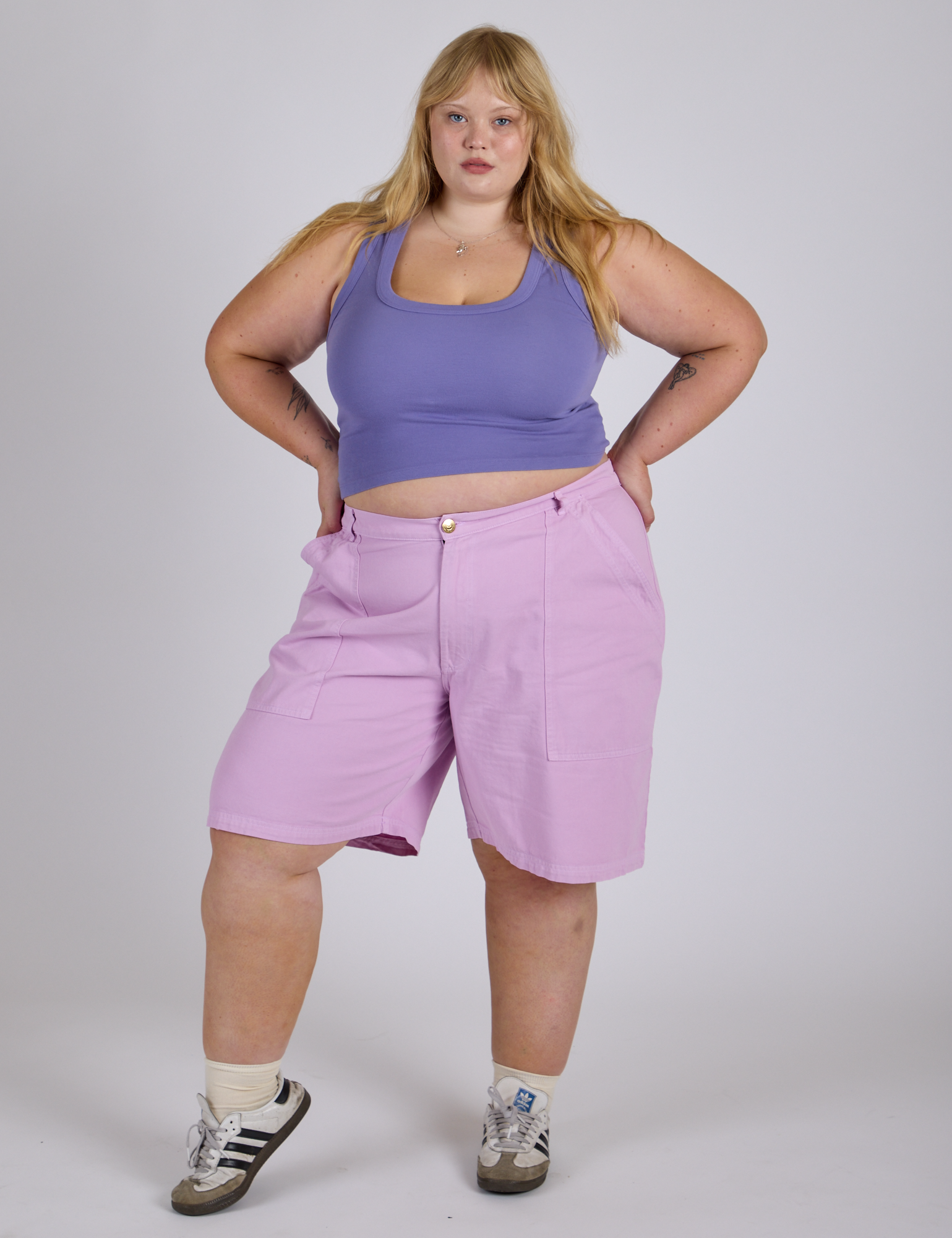 Juliet is 5’7” and wearing 2XL Longline Work Shorts in Lilac Purple paired with faded grape Cropped Tank