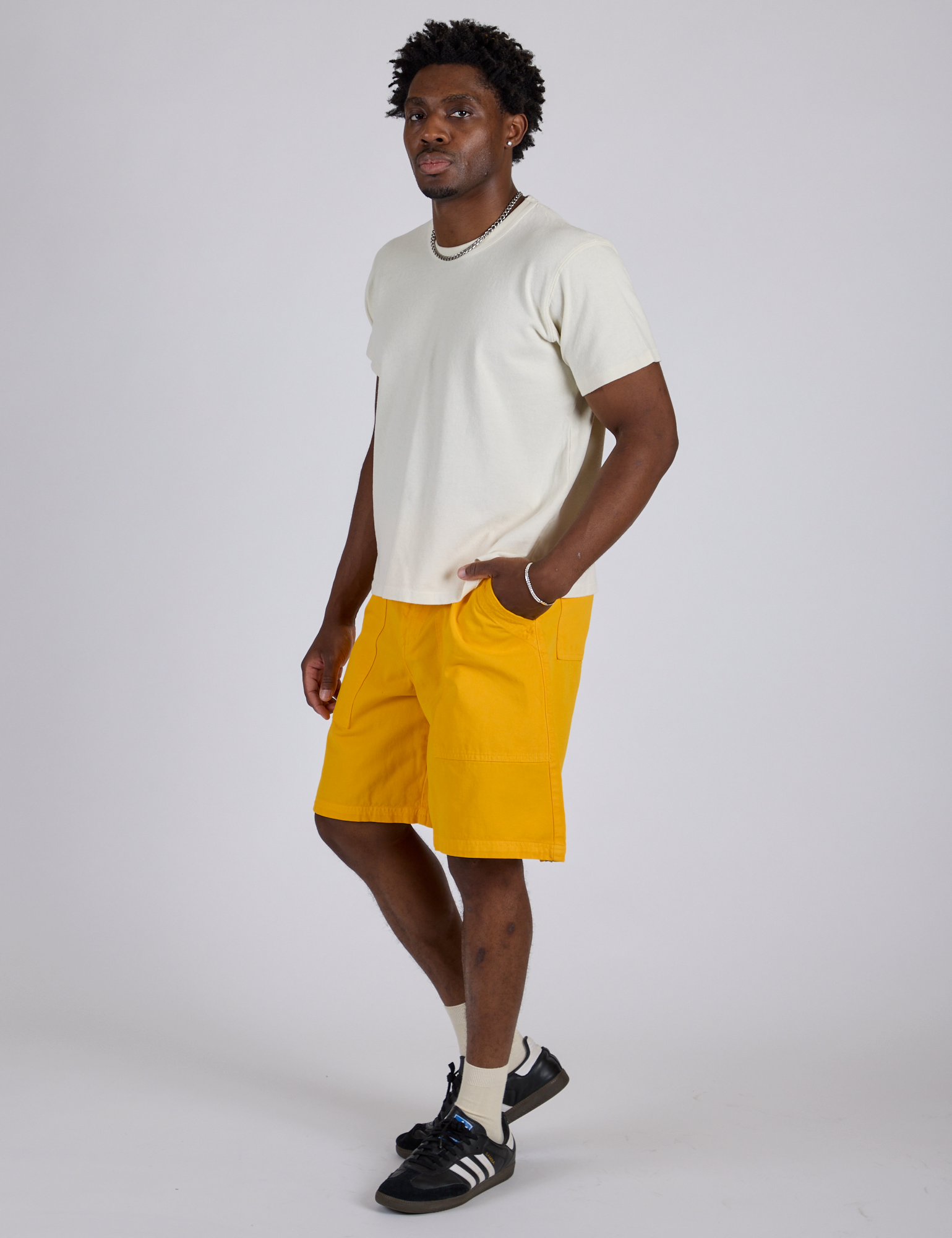 Angled front view of Longline Work Shorts in Sunshine Yellow and Burly Tee in Vintage Tee White on Isaac