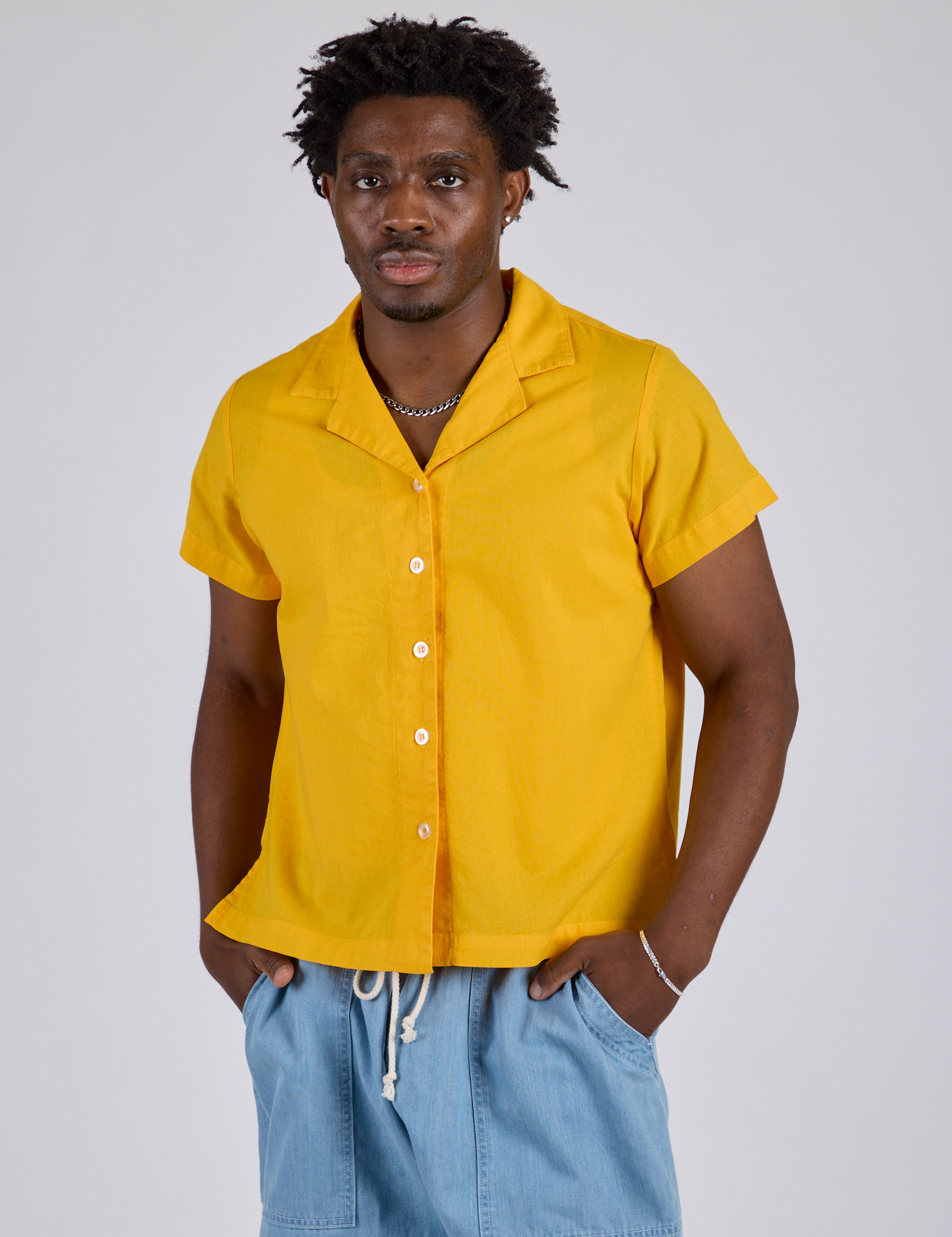 Isaac is wearing a buttoned up Pantry Button-Up in Sunshine Yellow