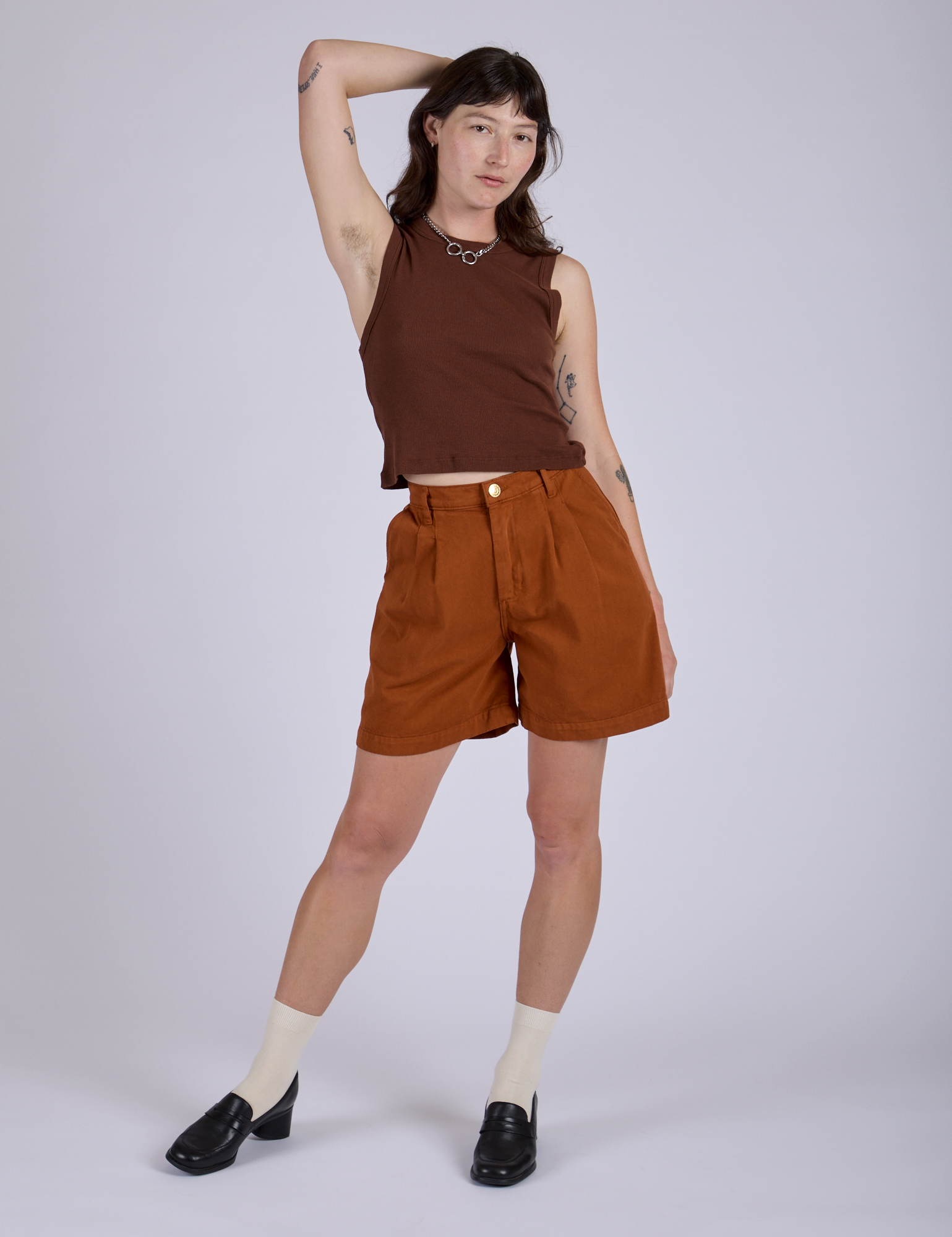 Alex is wearing Pleated Trouser Shorts in Burnt Terracotta and Muscle Tee in Fudgesicle Brown
