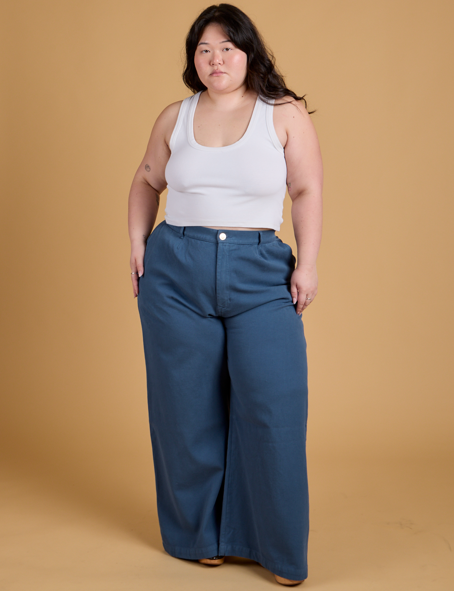 Ashley is 5'7" and wearing 1XL Heritage Wide Leg Trousers in French Blue paired with a vintage tee white Cropped Tank