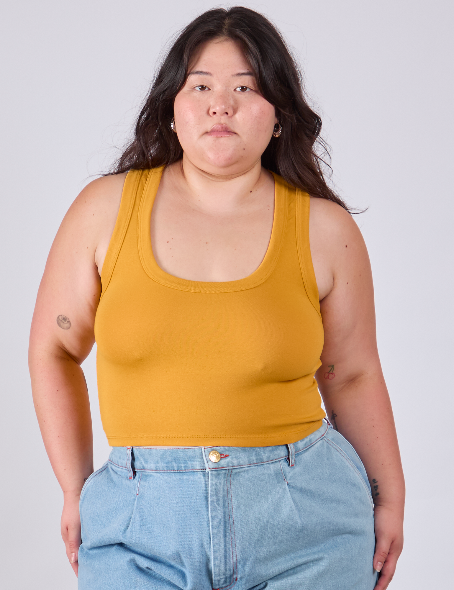 Ashley is 5'7" and wearing L Cropped Tank Top in Mustard Yellow