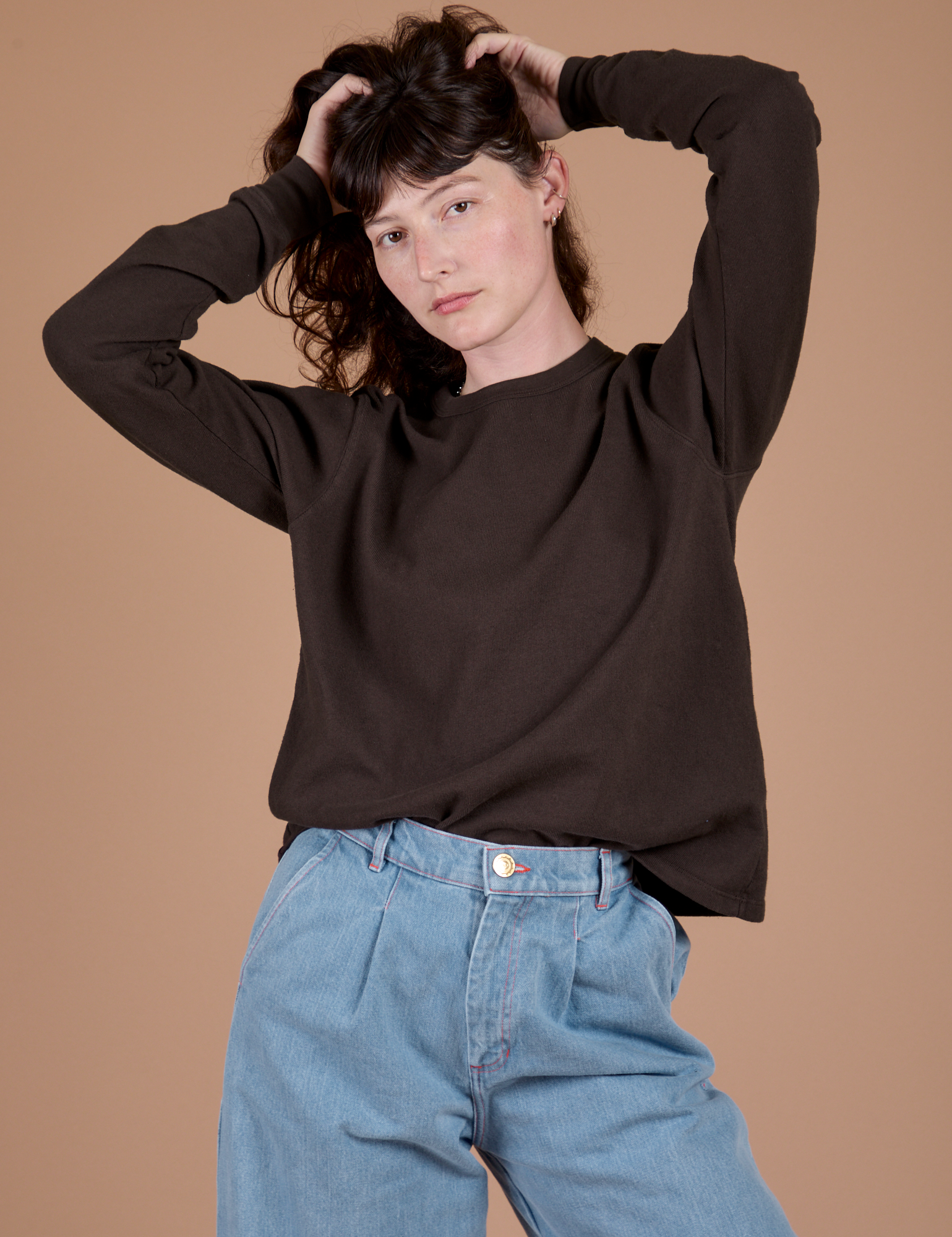 Alex is wearing Long Sleeve Burly Tee in Espresso Brown tucked into light wash Indigo Wide Leg Trousers