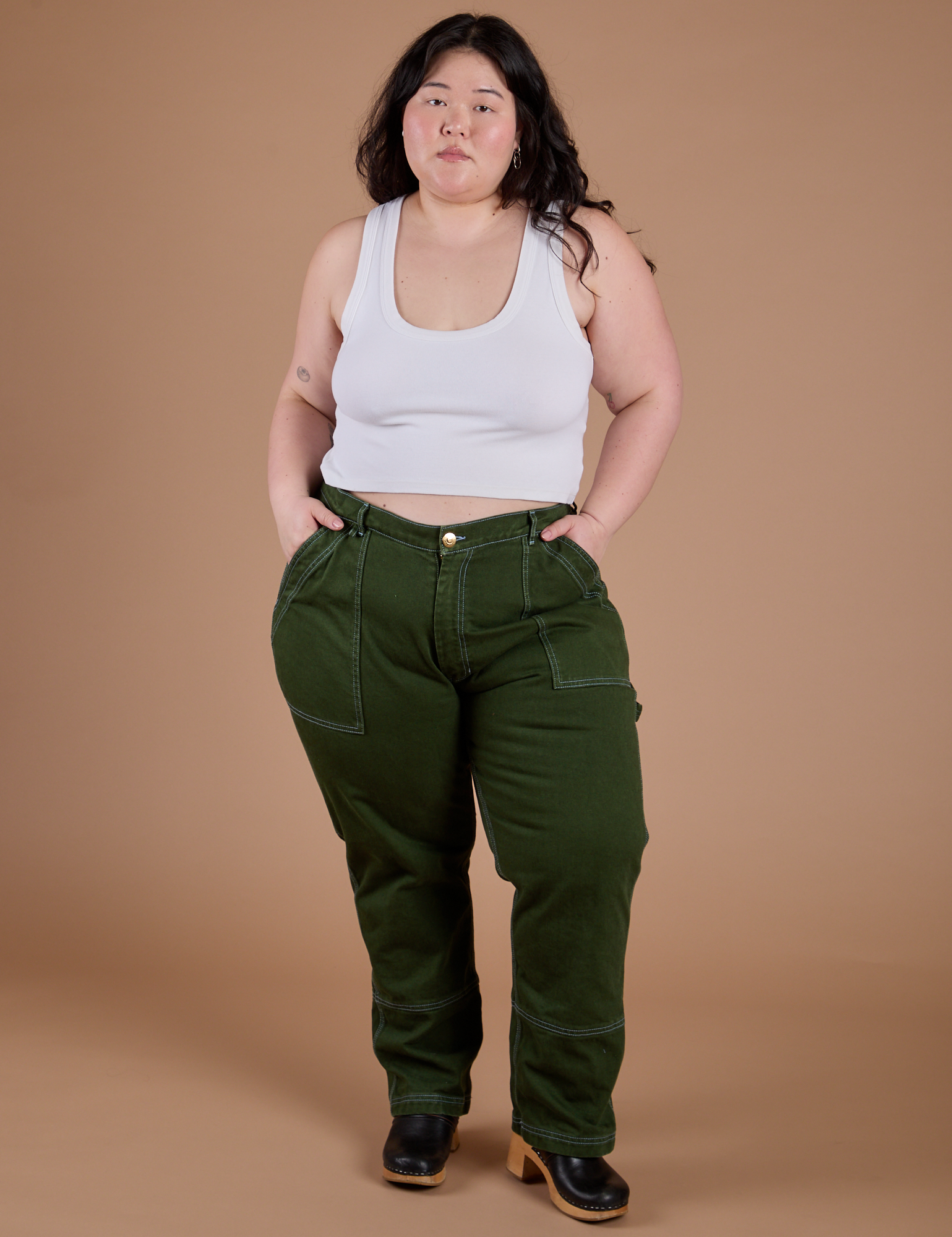 Ashley is 5’7” and wearing 1XL Carpenter Jeans in Evergreen paired with a Cropped Tank in Vintage Tee White