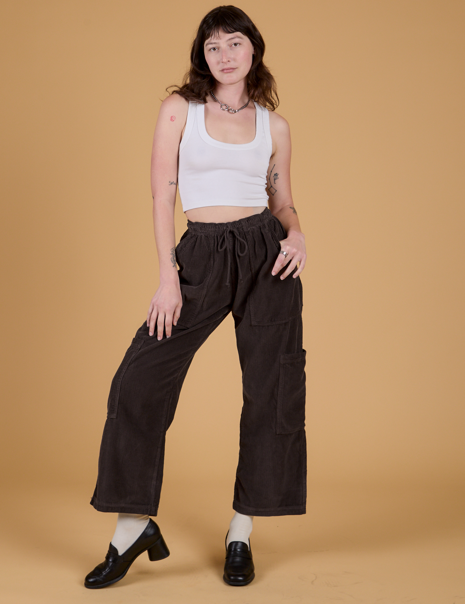 Alex is 5’8” and wearing XXS Corduroy Drop Pocket Cargo Pants in Espresso Brown paired with a Cropped Tank in Vintage Tee White
