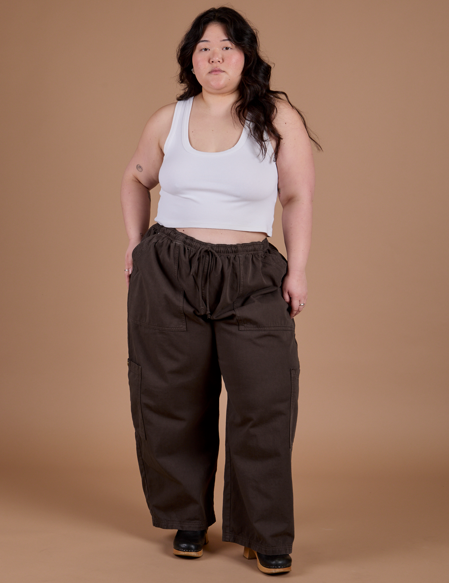 Ashley is 5'7" and wearing 1XL Drop Pocket Cargo Pants in Espresso Brown paired with a vintage tee white Cropped Tank