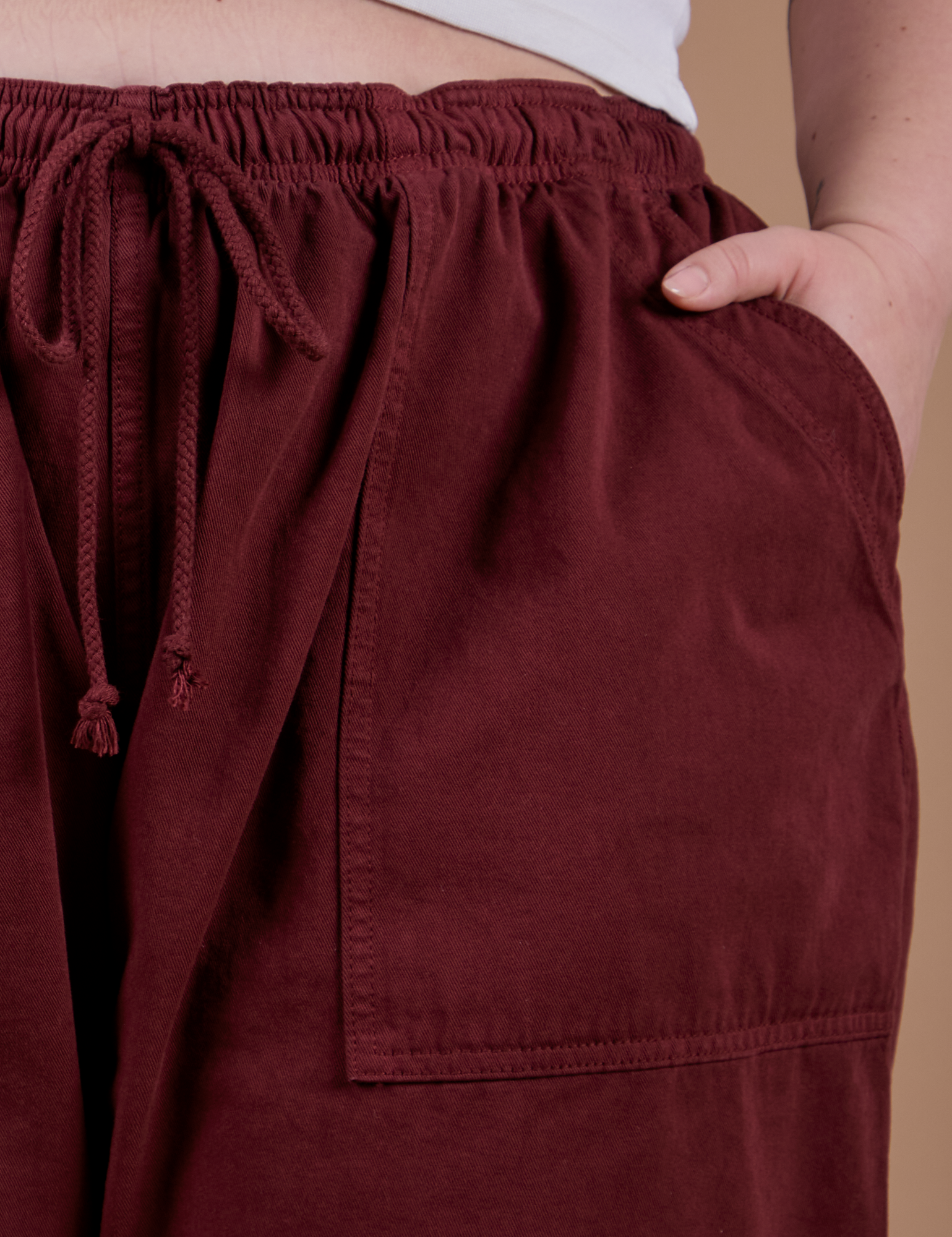 Drop Pocket Cargo Pants in Red Wine front pocket close up with Ashley's hand tucked in