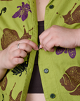 Close up of Ashley buttoning the Paintstamped Pantry Button-Up in Big Bug