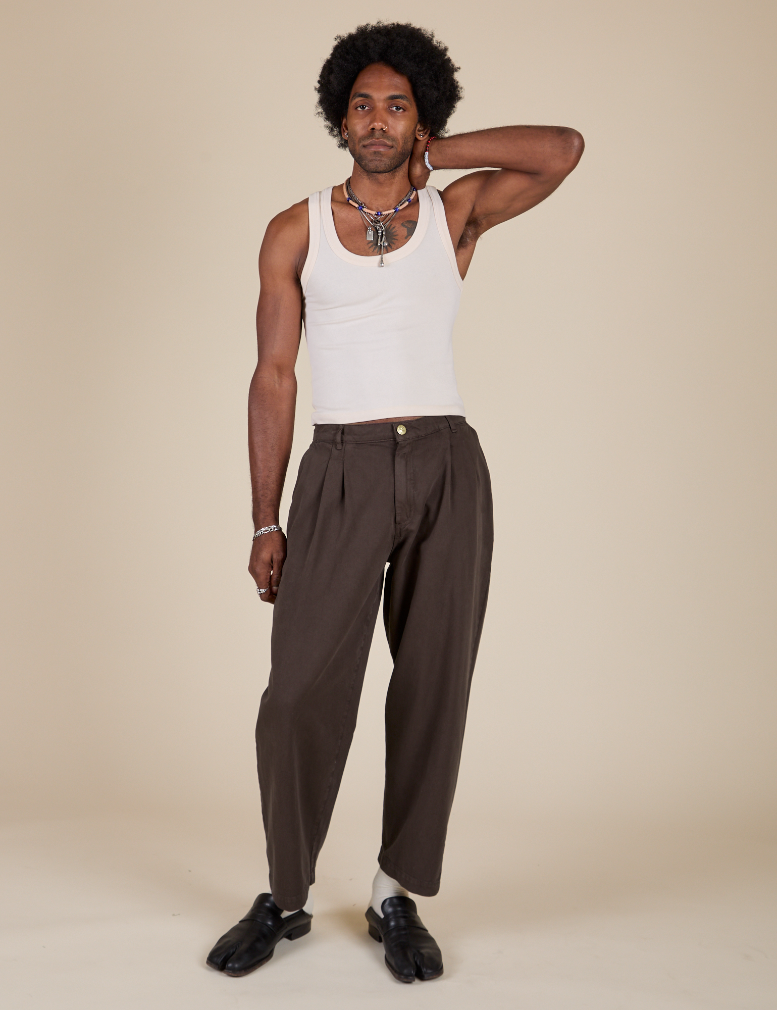 Jerrod is 6'3" and wearing M Heavyweight Trousers in Espresso Brown paired with a Tank Top in Vintage Tee Off-White