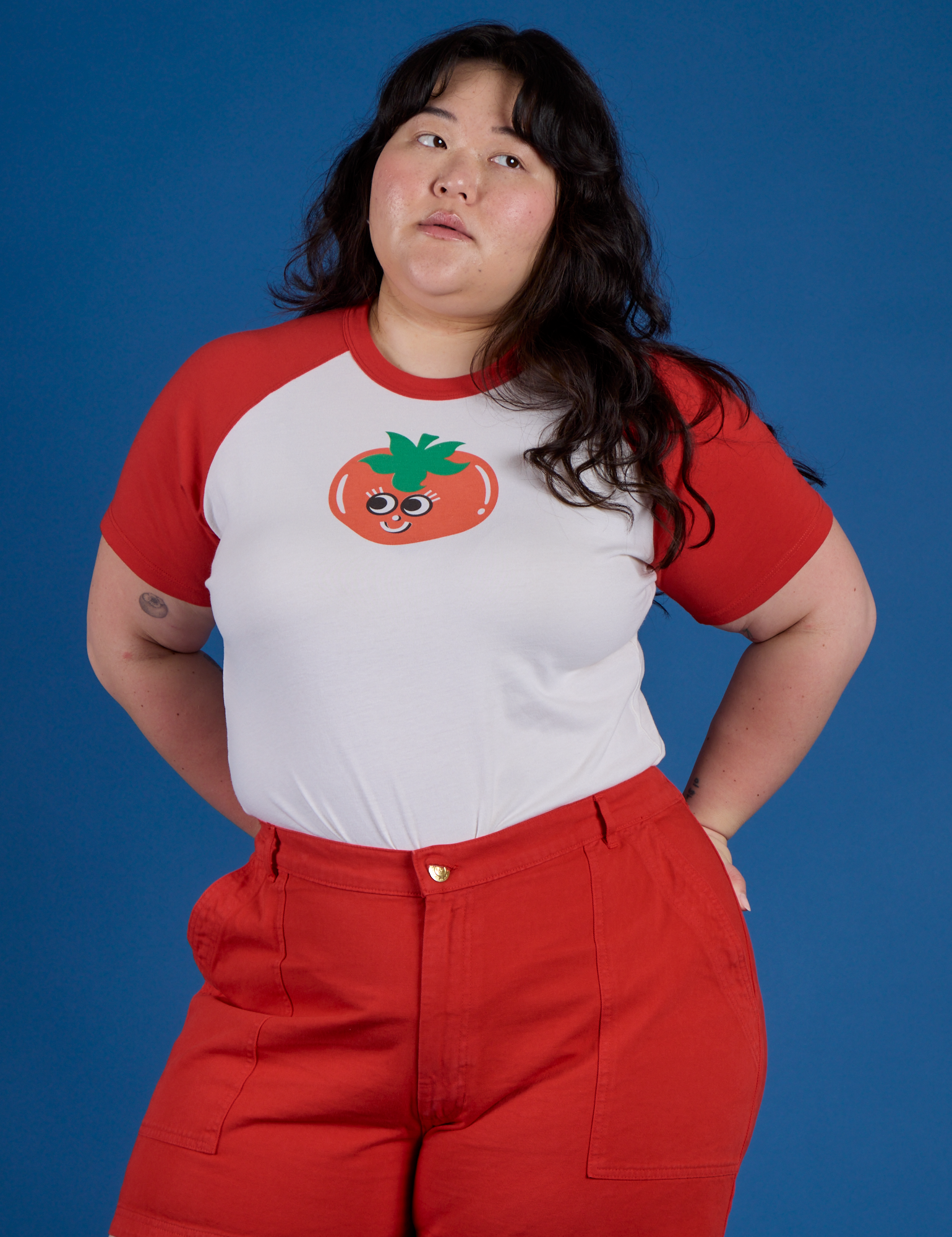 Ashley is wearing Produce Raglan Tee in Tomato tucked into mustang red Work Pants