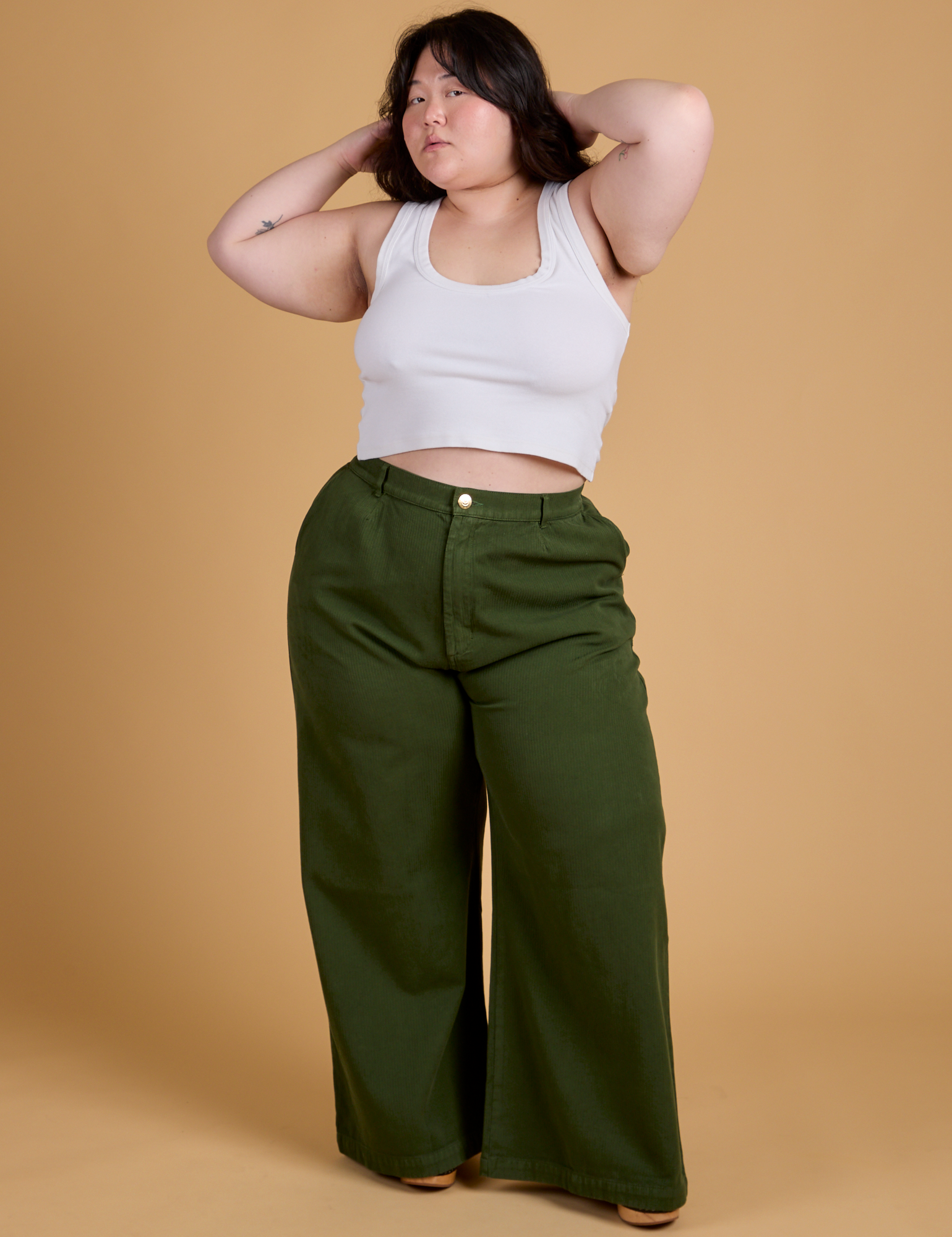 Ashley is 5'7" and wearing 1XL Heritage Wide Leg Trousers in Evergreen paired with vintage tee white Cropped Tank