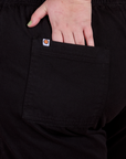 Close up of Juliet's hand in the back pocket of Action Pants in Basic Black