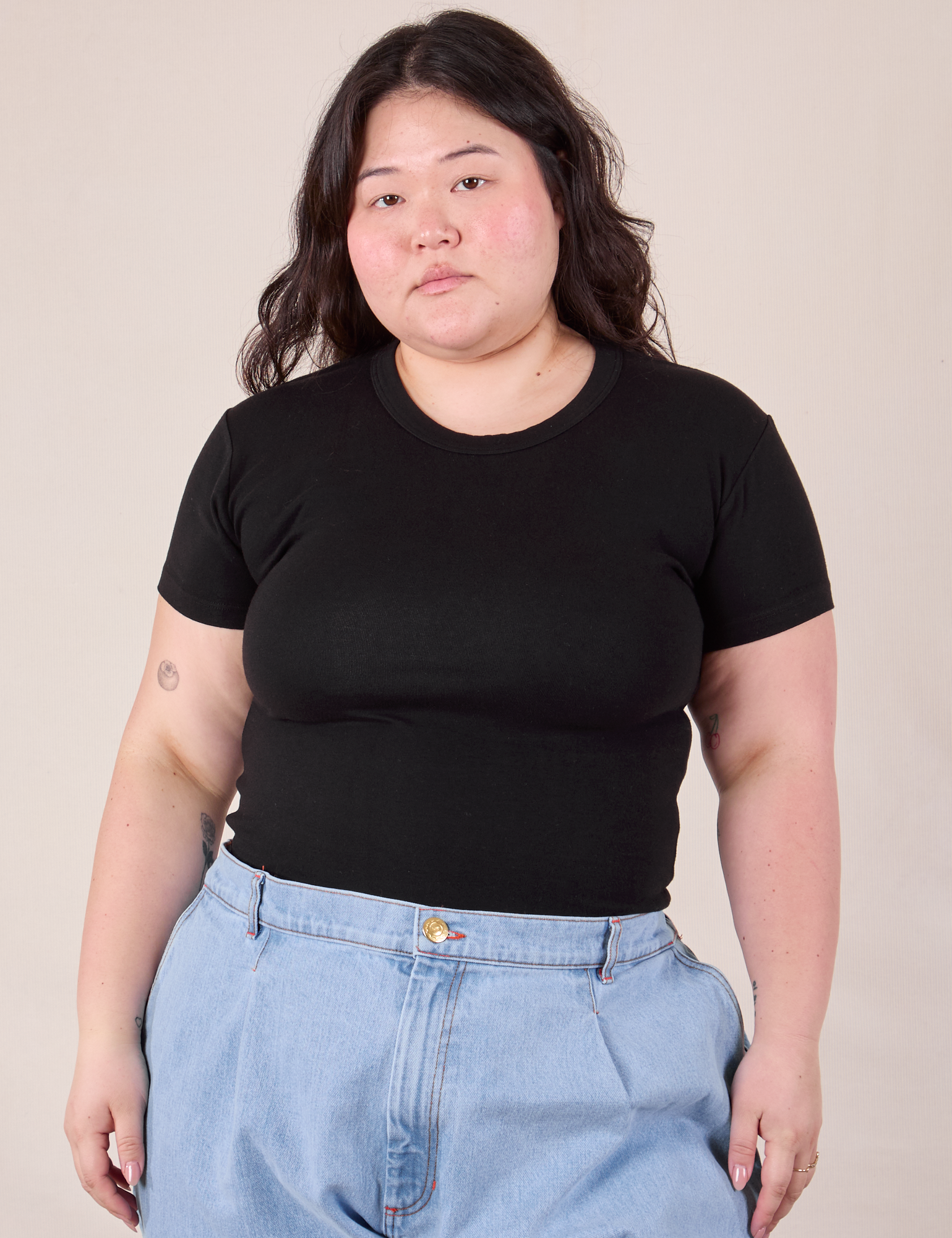 Ashley is wearing Baby Tee in Vintage Basic Black tucked into light wash Denim Trousers