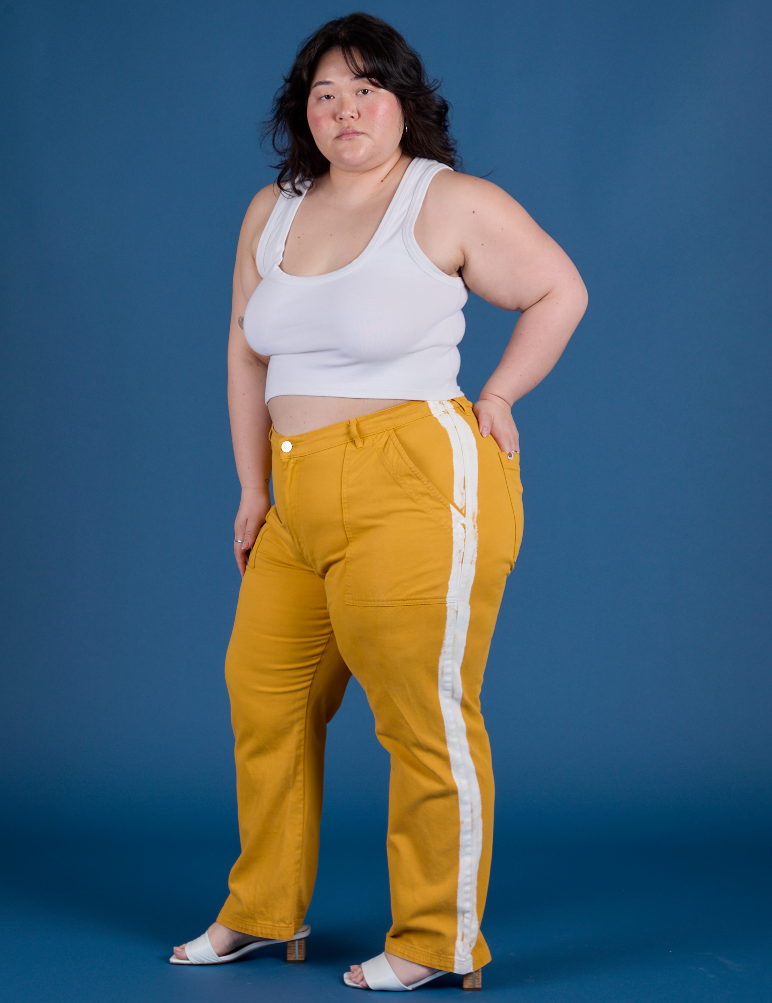 Angled front view of Painted Work Pants in Mustard Yellow and vintage tee white Cropped Tank on Ashley