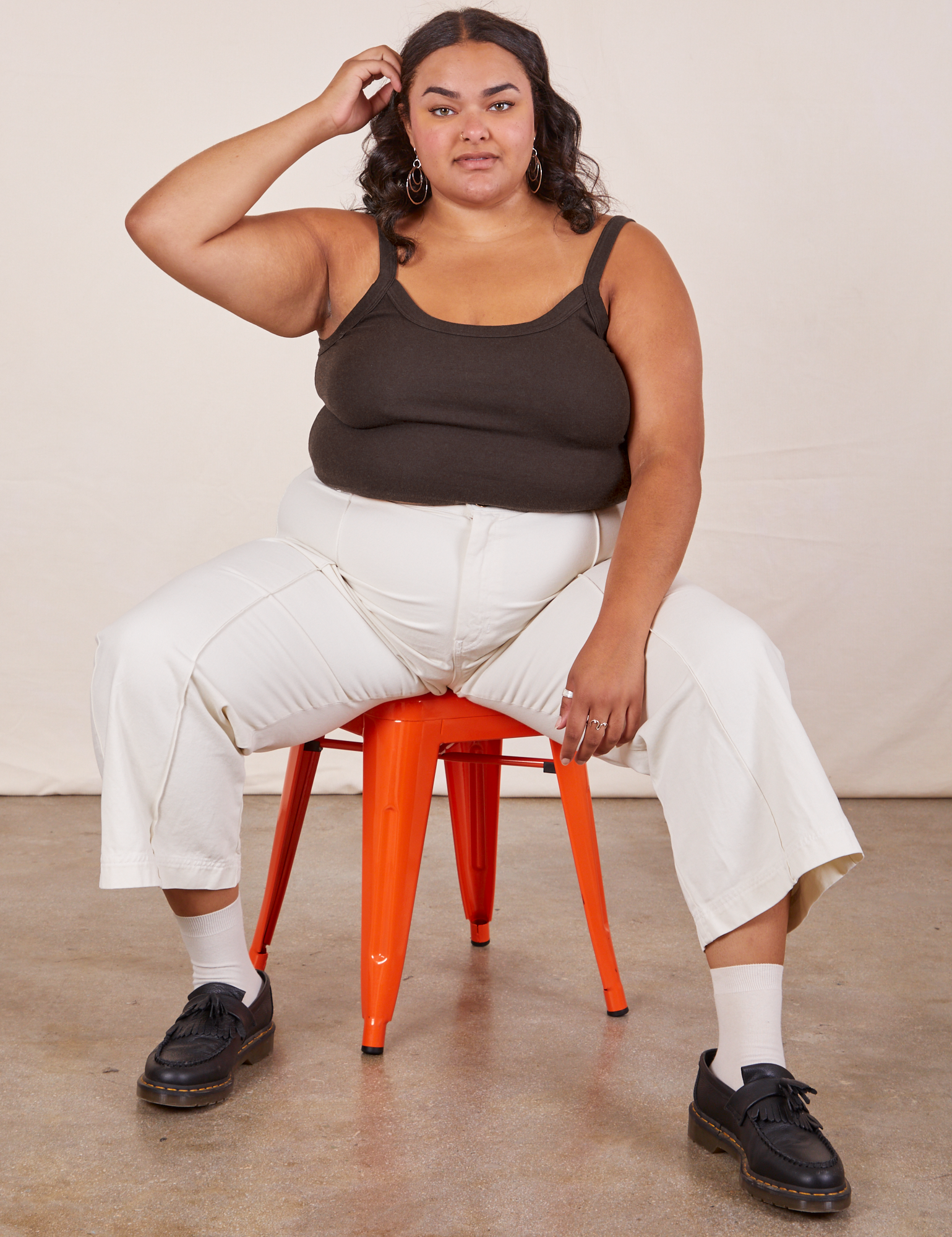 Alicia is sitting on an orange metal stool wearing Cropped Cami in Espresso Brown and vintage tee off-white Western Pants