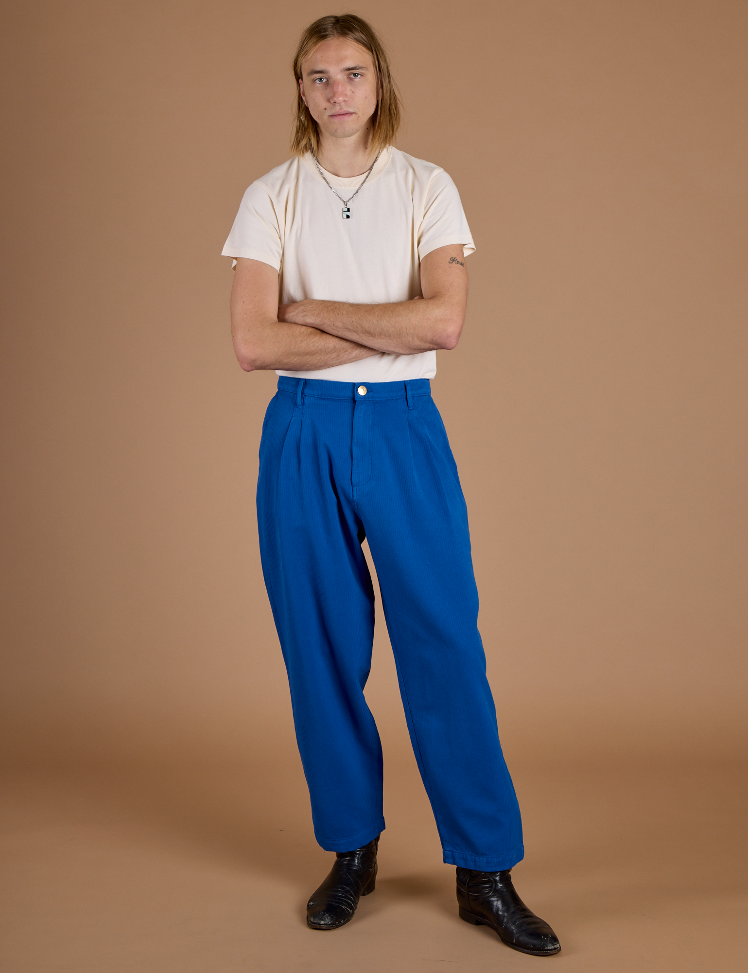 Grant is wearing Heritage Trousers in Royal Blue with a tucked in Organic Vintage Tee in Vintage Off White