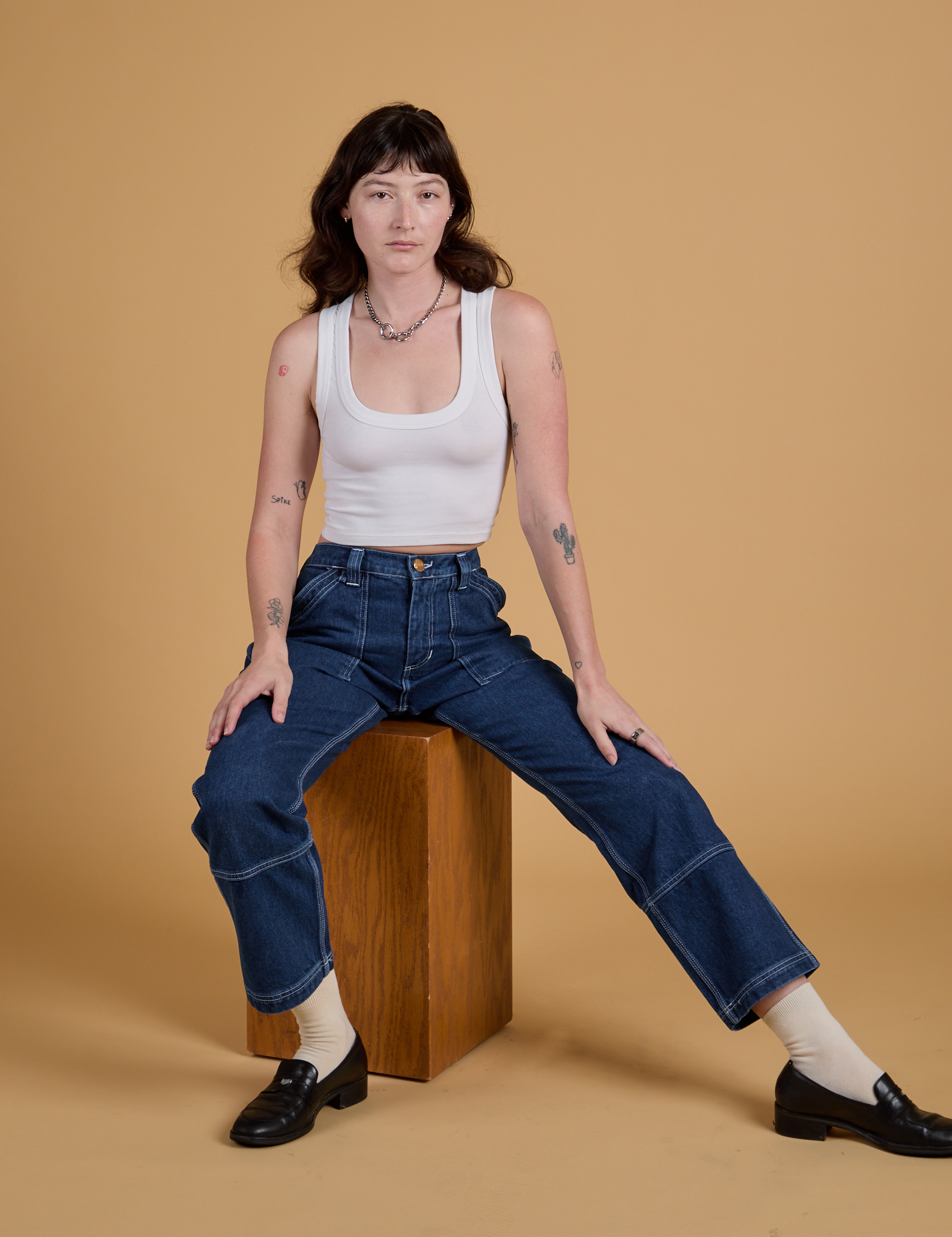 Alex is wearing Mid-Rise Carpenter Jeans in Dark Wash and Cropped Tank in Vintage Tee White