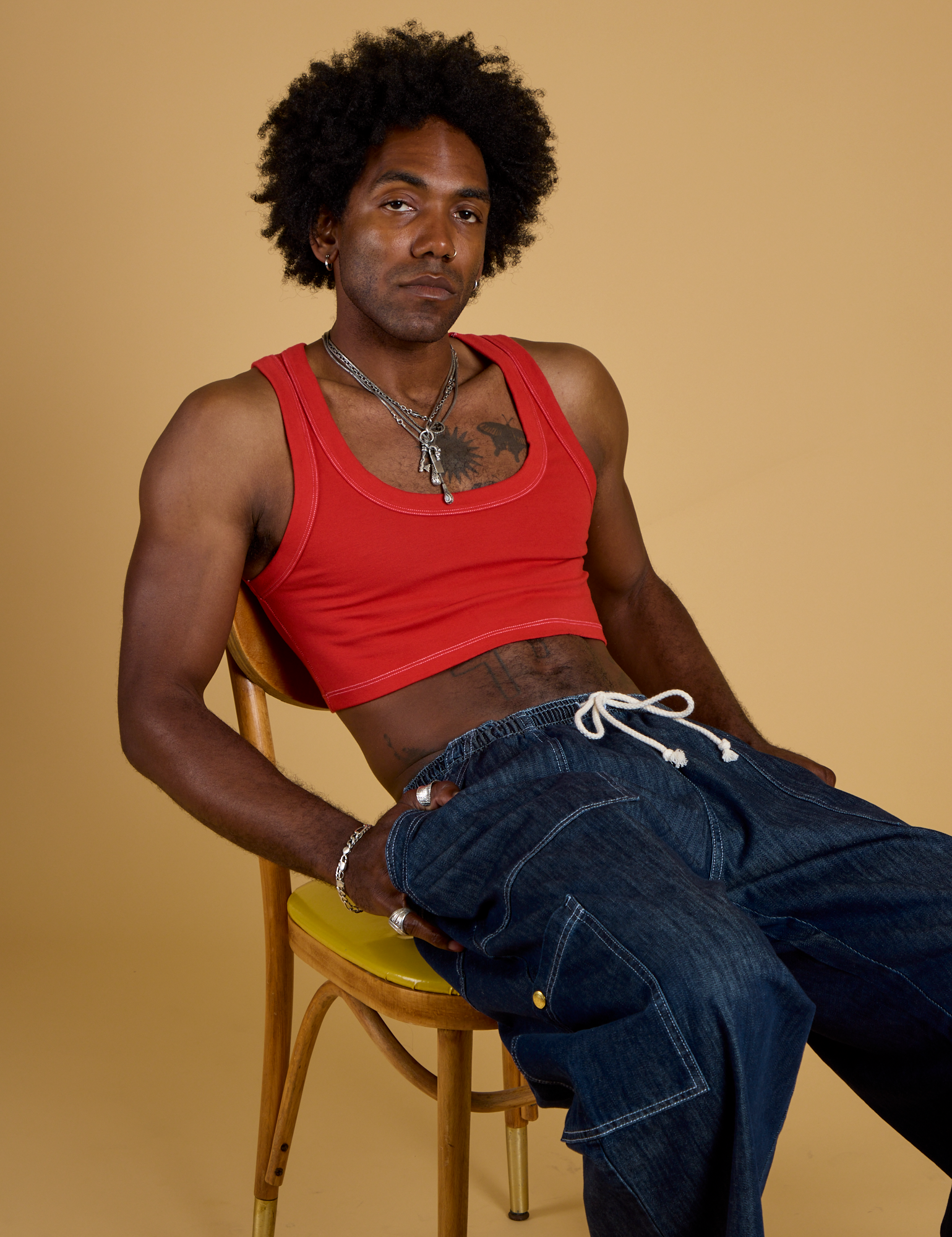 Jerrod is wearing Contrast Stitch Mini Tank in Mustang Red and dark wash Denim Drop Pocket Pants