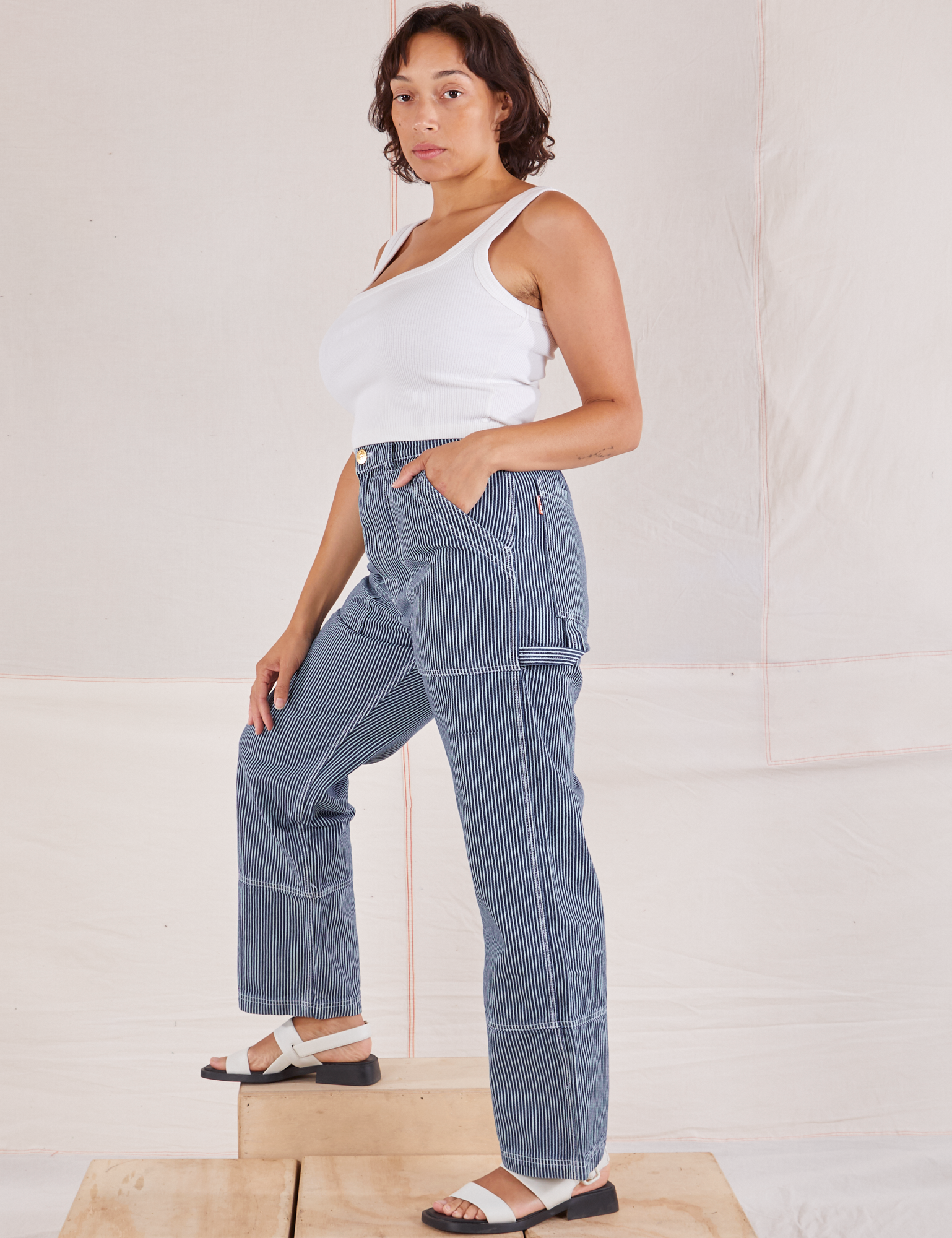 Side view of Carpenter Jeans in Indigo Railroad and vintage tee off-white Square Neck Tank