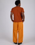Back view of Drop Pocket Cargo Pants in Creamsicle Orange and burnt terracotta Organic Vintage Tee on Isaac