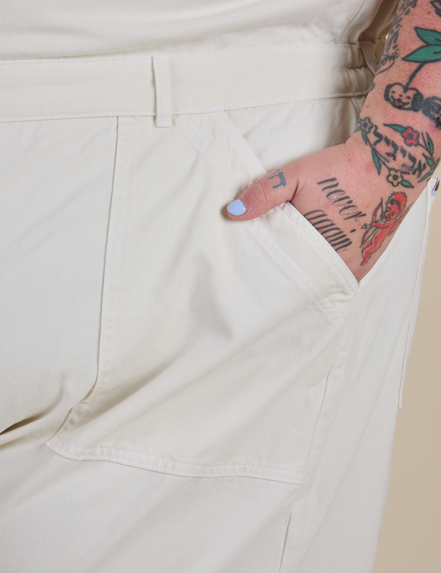 Close up of Sam's hand in the front pocket of Short Sleeve Jumpsuit in Vintage Tee White