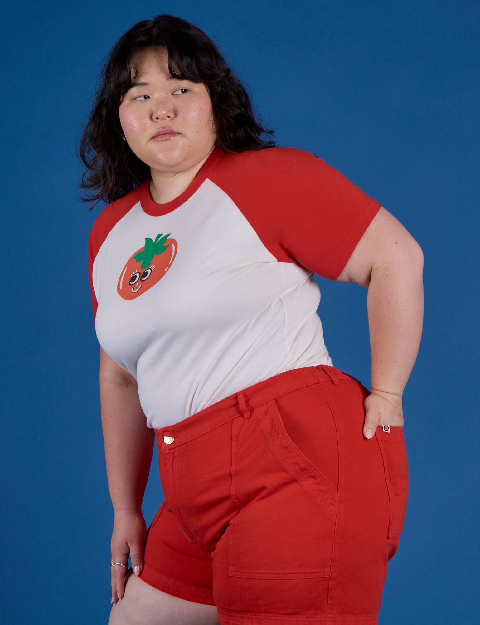 Angled front view of Produce Raglan Tee in Tomato on Ashley