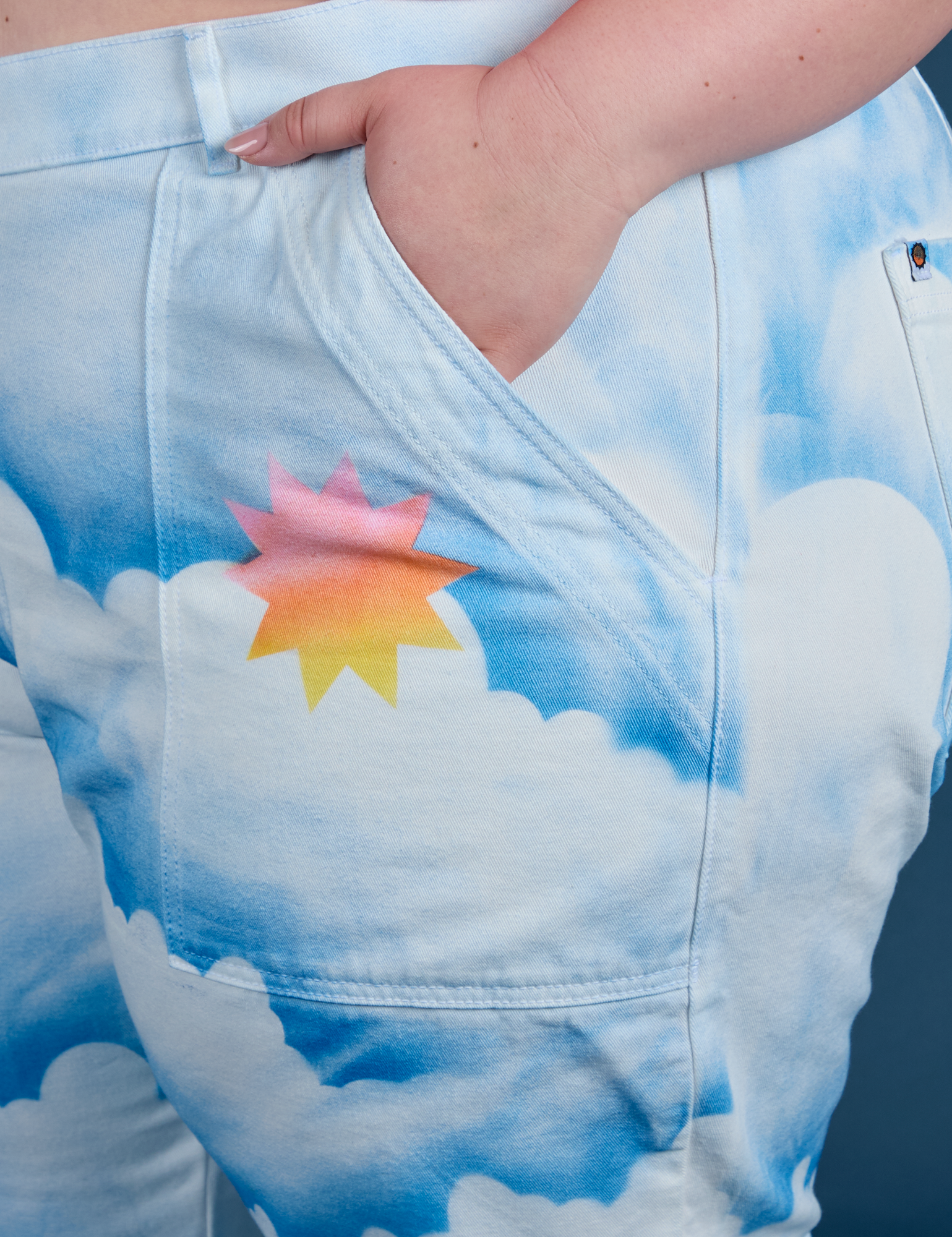 Close up of Ashley's hand in the front pocket of Work Pants in Sunny Cloud Airbrush