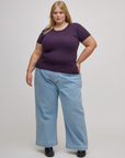 Juliet is wearing Baby Tee in Nebula Purple and light wash denim wide leg trousers