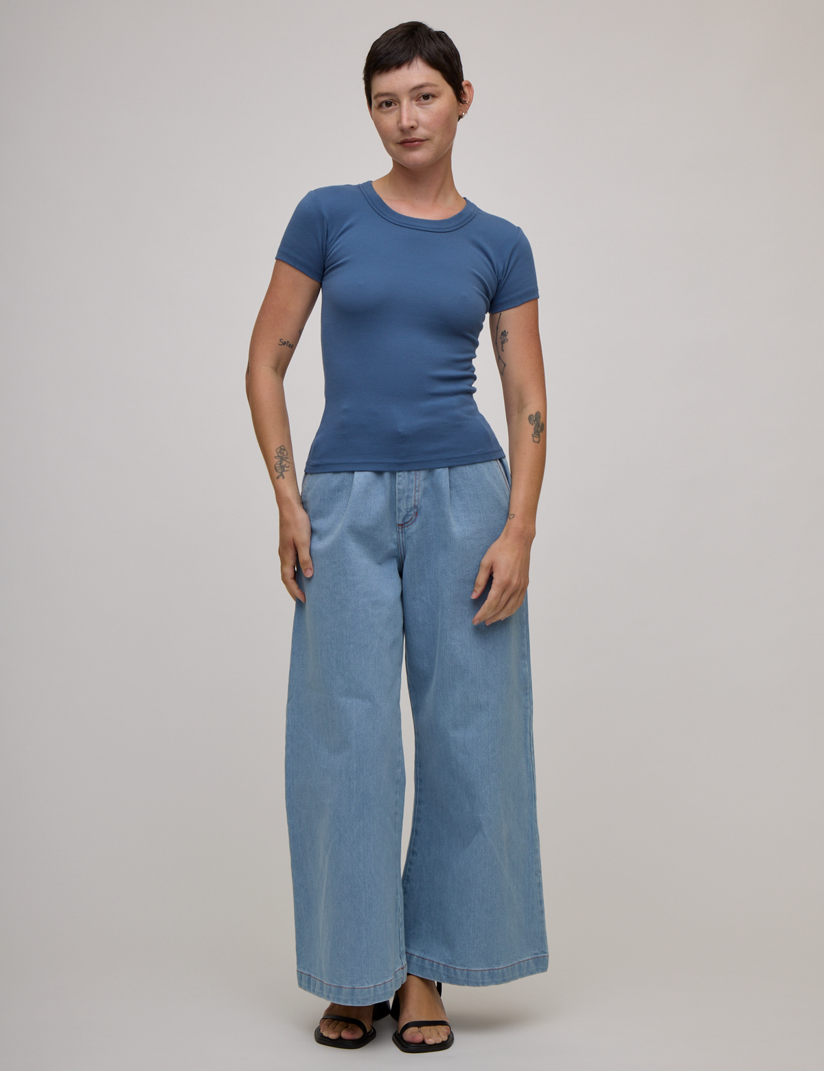 Alex is 5'8" and wearing P Baby Tee in French Blue paired with light wash denim wide leg trousers