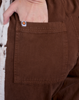 Close up of Alex's hand in the back pocket of Painted Action Pants in Fudgesicle Brown